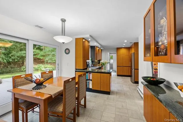 Kitchen and dining area featuring wood-finish cabinetry, and integrated stainless steel appliances Kitchen and dining area featuring wood-finish cabinetry, and integrated stainless steel appliances
