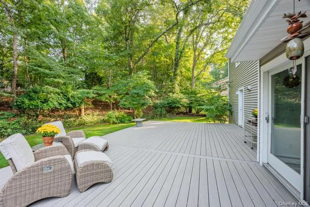 Expansive deck with slatted surface, bordered by a lush, green landscape and mature trees Expansive deck with slatted surface, bordered by a lush, green landscape and mature trees