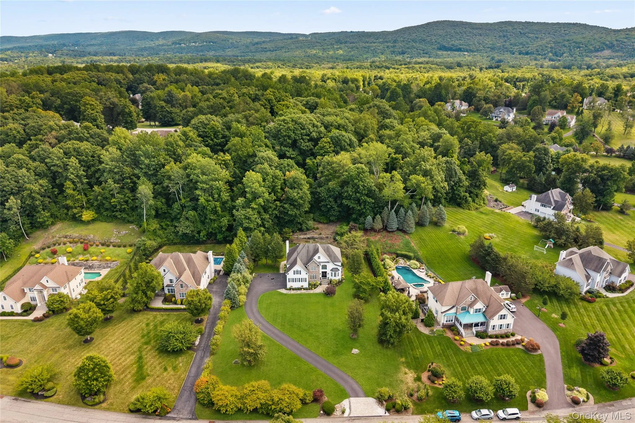 Aerial view of residential area with a heavily wooded area and mountains Aerial view of residential area with a heavily wooded area and mountains