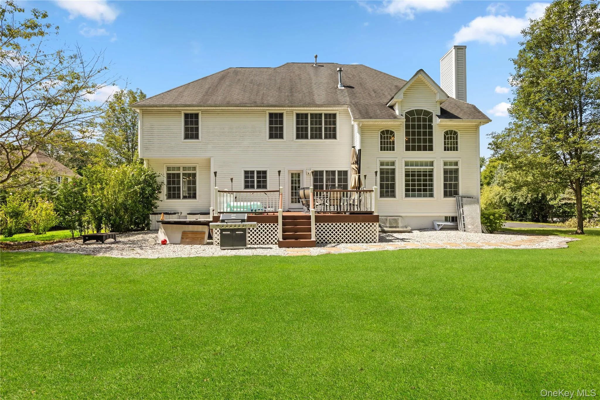 Back of property featuring a chimney, a deck, a yard, and a patio area Back of property featuring a chimney, a deck, a yard, and a patio area