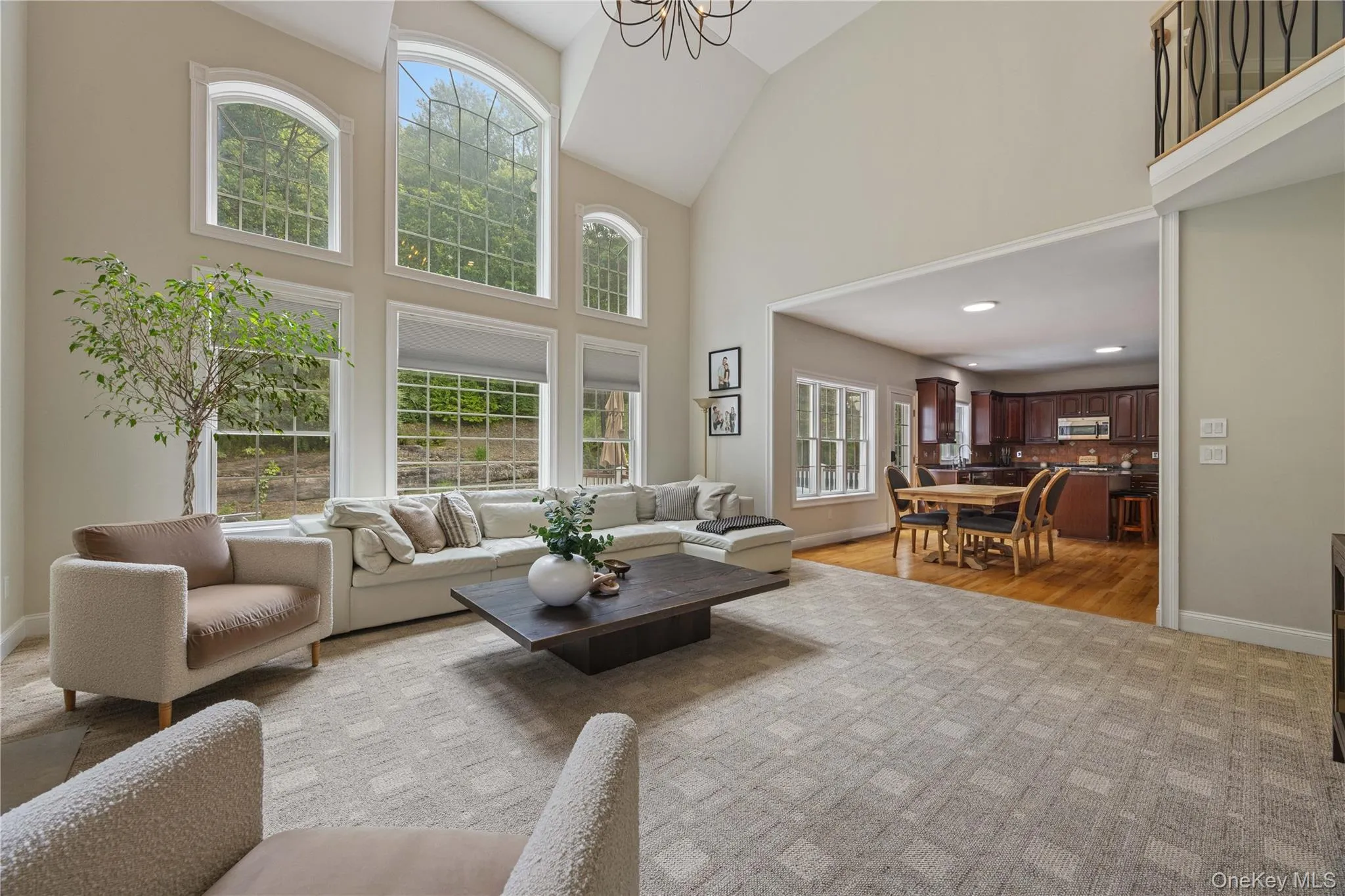 Living area featuring high vaulted ceiling, a chandelier, and light wood-style floors Living area featuring high vaulted ceiling, a chandelier, and light wood-style floors