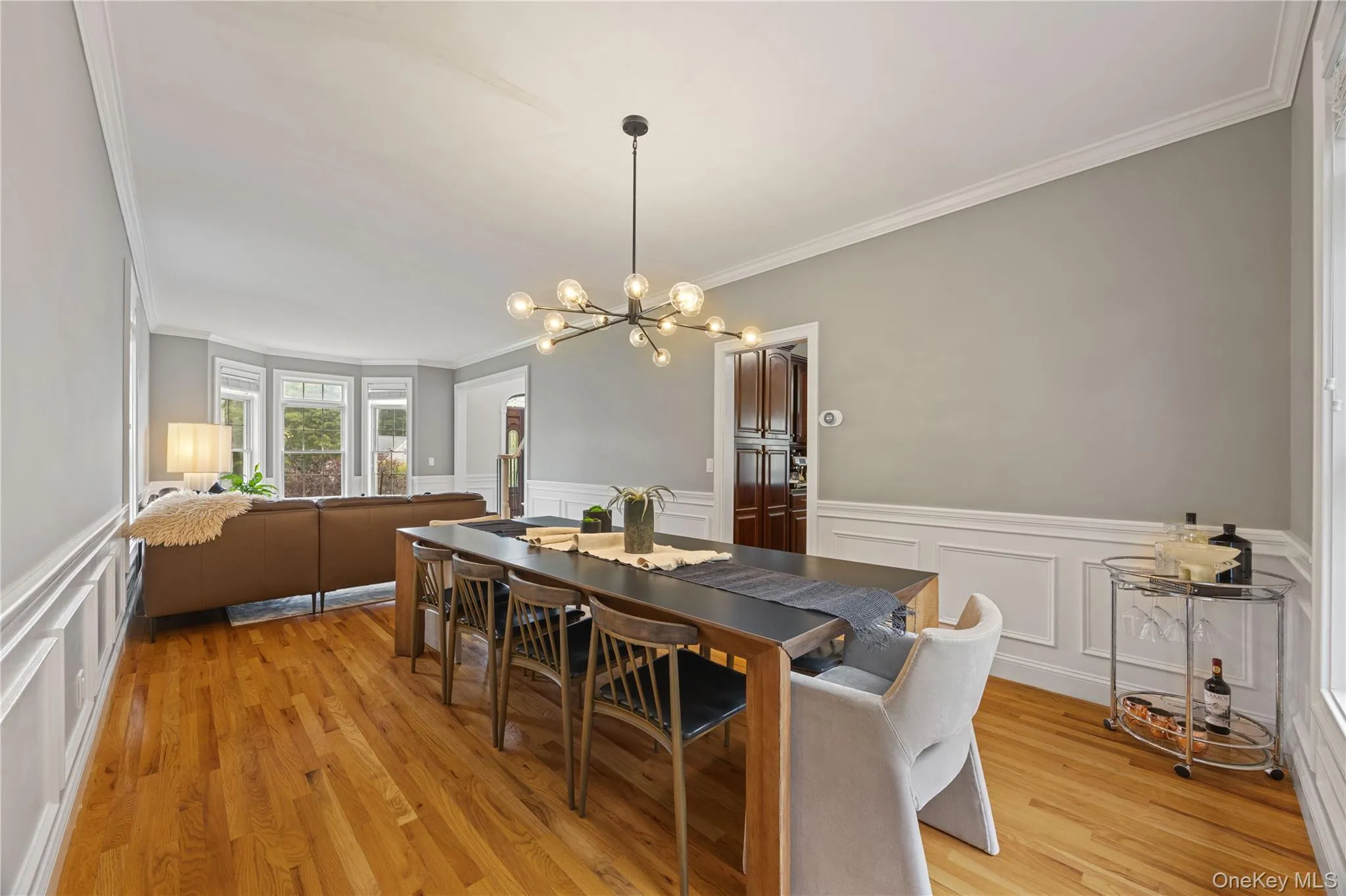 Dining space featuring ornamental molding, a decorative wall, a chandelier, light wood-style flooring, and a wainscoted wall Dining space featuring ornamental molding, a decorative wall, a chandelier, light wood-style flooring, and a wainscoted wall