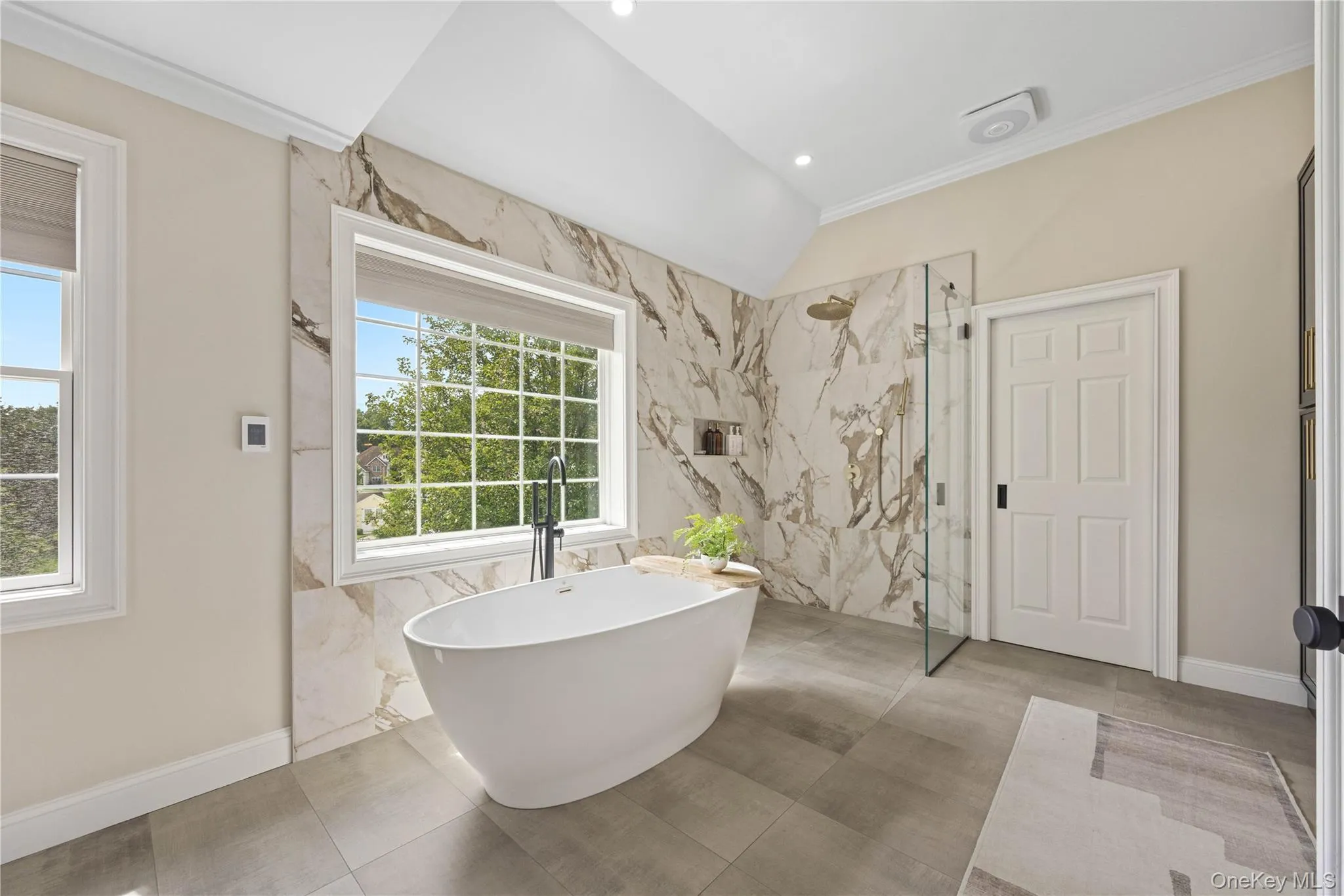 Bathroom featuring a marble finish shower, a soaking tub, crown molding, tile walls, and vaulted ceiling Bathroom featuring a marble finish shower, a soaking tub, crown molding, tile walls, and vaulted ceiling