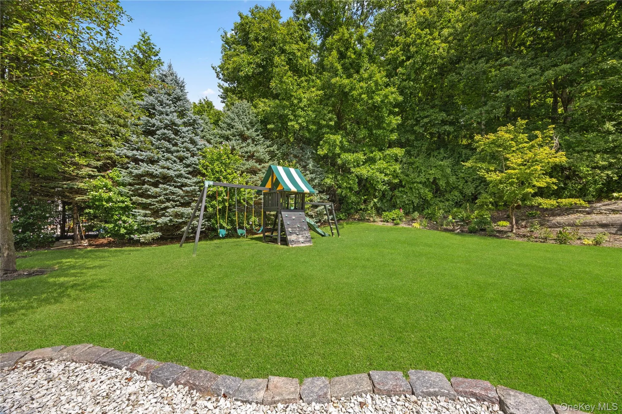 View of grassy yard with a playground and view of scattered trees View of grassy yard with a playground and view of scattered trees