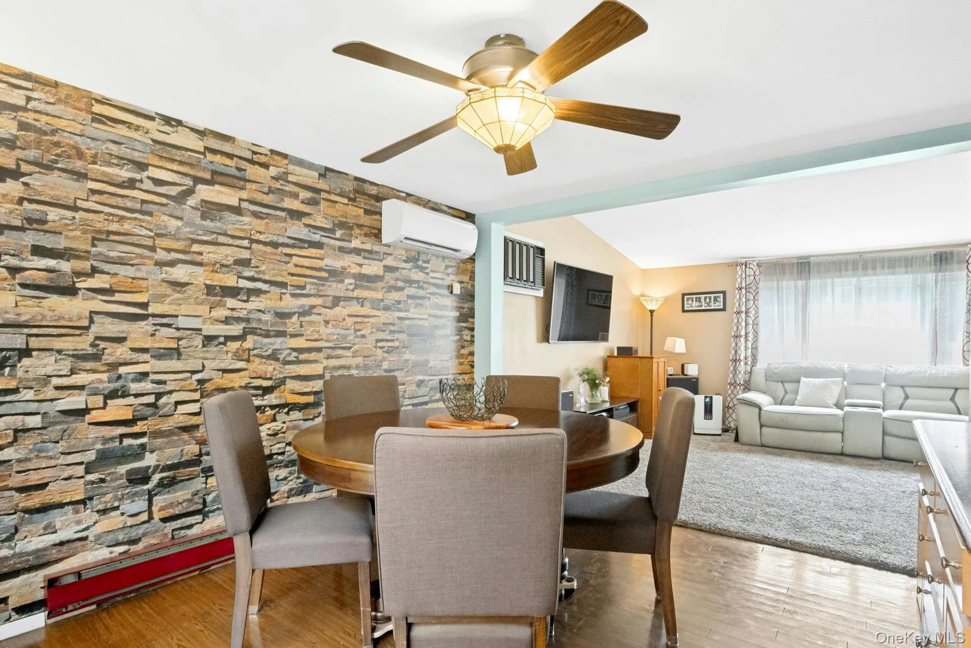 Spacious dining room with decorative stone accent wall, ceiling fan, and open flow to the living room. Spacious dining room with decorative stone accent wall, ceiling fan, and open flow to the living room.