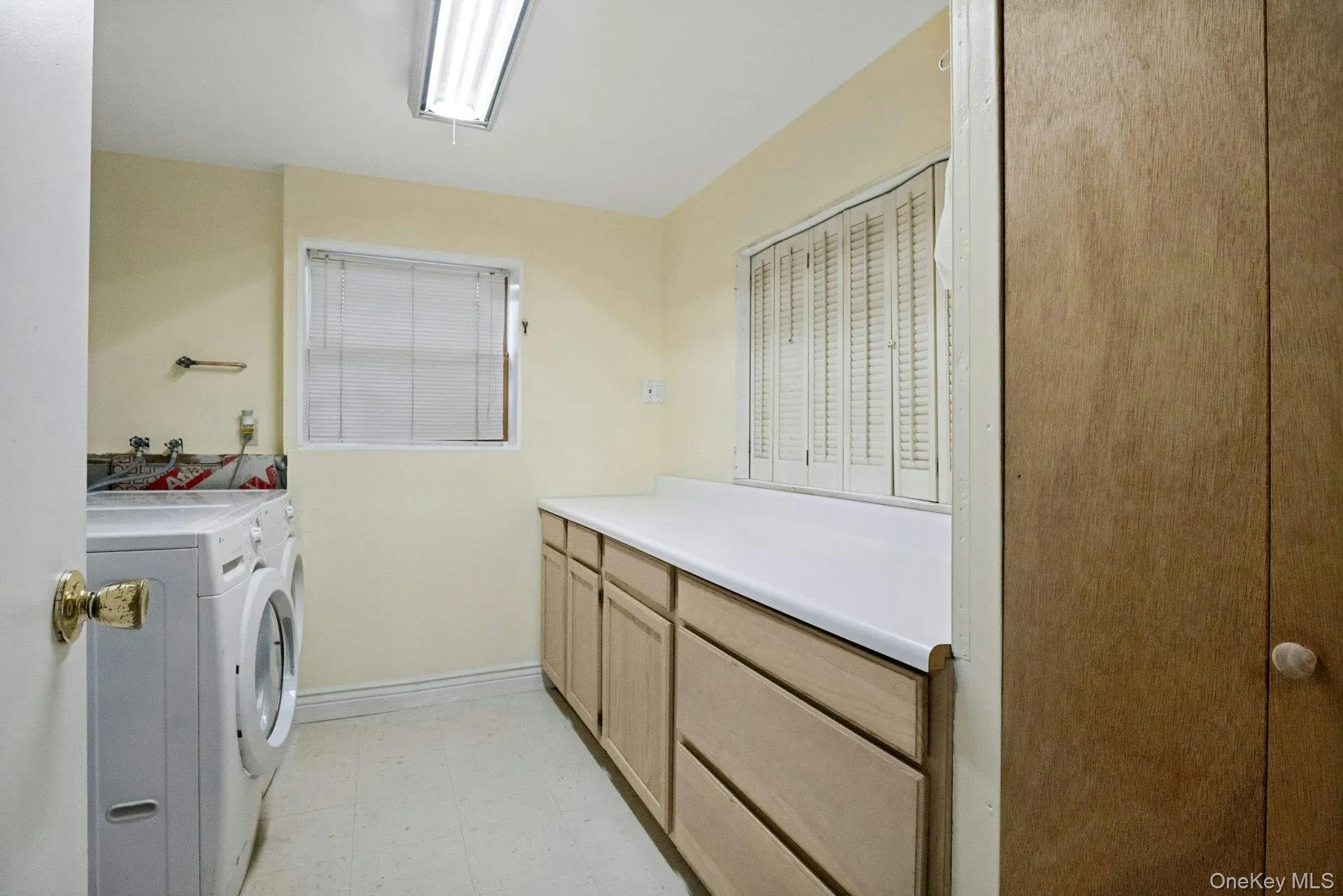 Spacious lower-level laundry room with washer and dryer, extensive counter space, cabinetry, and additional storage. Spacious lower-level laundry room with washer and dryer, extensive counter space, cabinetry, and additional storage.