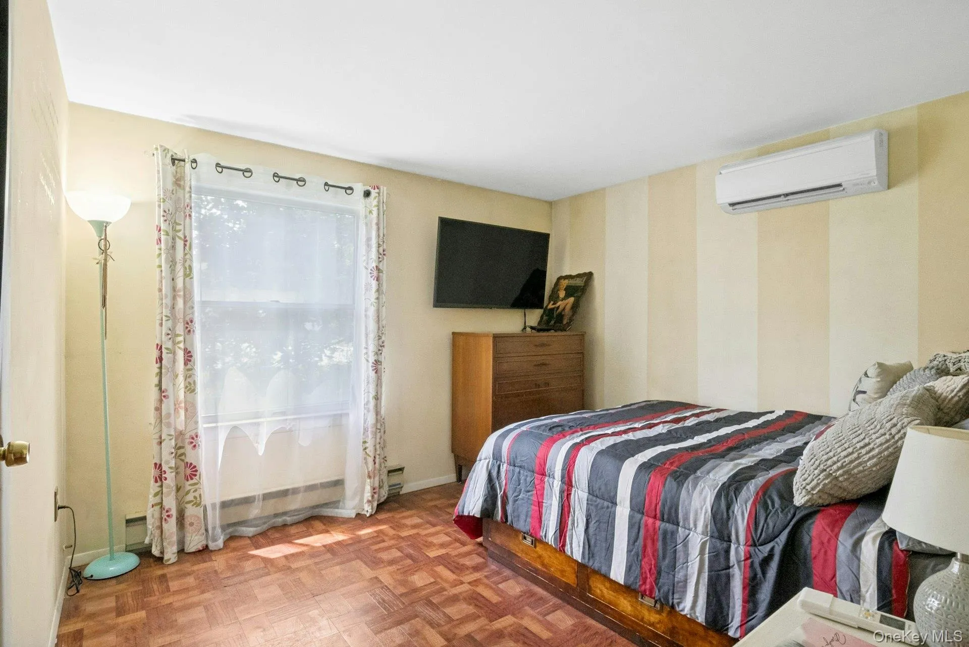 Bedroom with wood-look flooring, front-facing window, and ductless heating and cooling Bedroom with wood-look flooring, front-facing window, and ductless heating and cooling