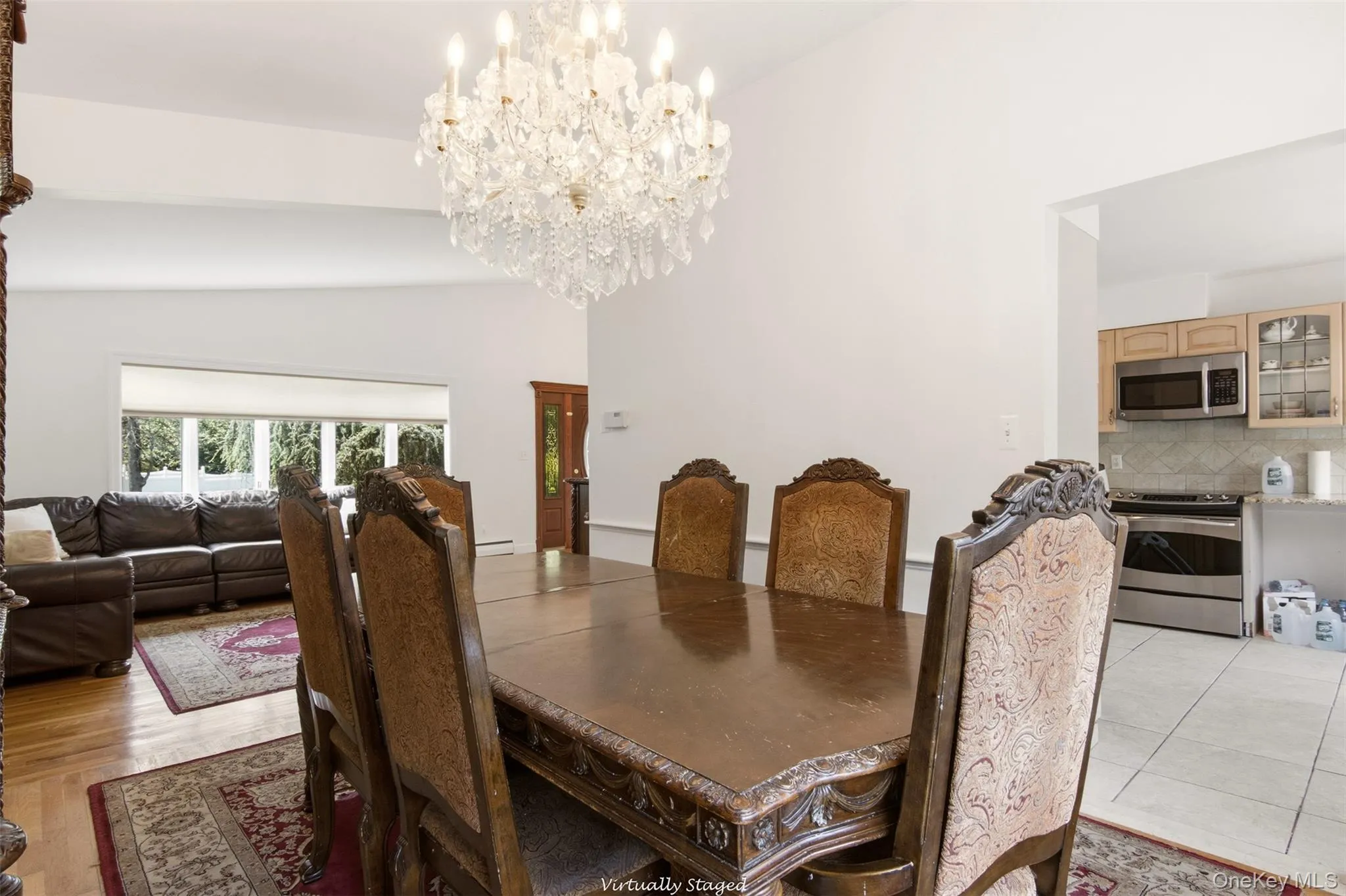 Vaulted ceiling with a crystal chandelier, wood-finish flooring, bay window, kitchen with stainless steel appliances, and wood cabinetry Vaulted ceiling with a crystal chandelier, wood-finish flooring, bay window, kitchen with stainless steel appliances, and wood cabinetry