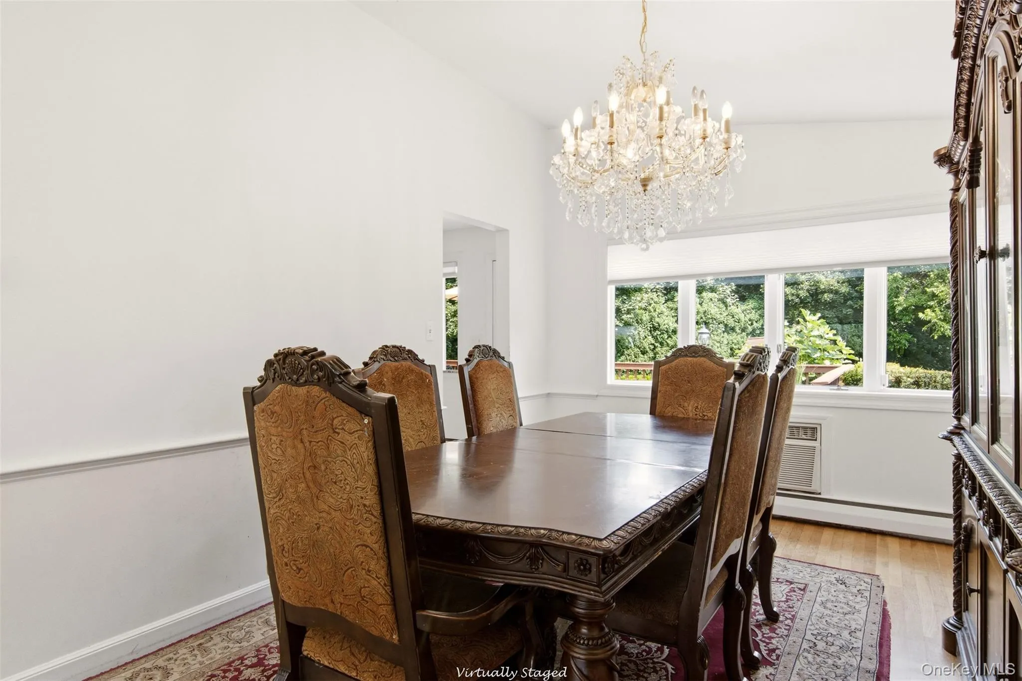 Hardwood flooring, crown molding, chair rail, and an ornate crystal chandelier illuminate the space Hardwood flooring, crown molding, chair rail, and an ornate crystal chandelier illuminate the space