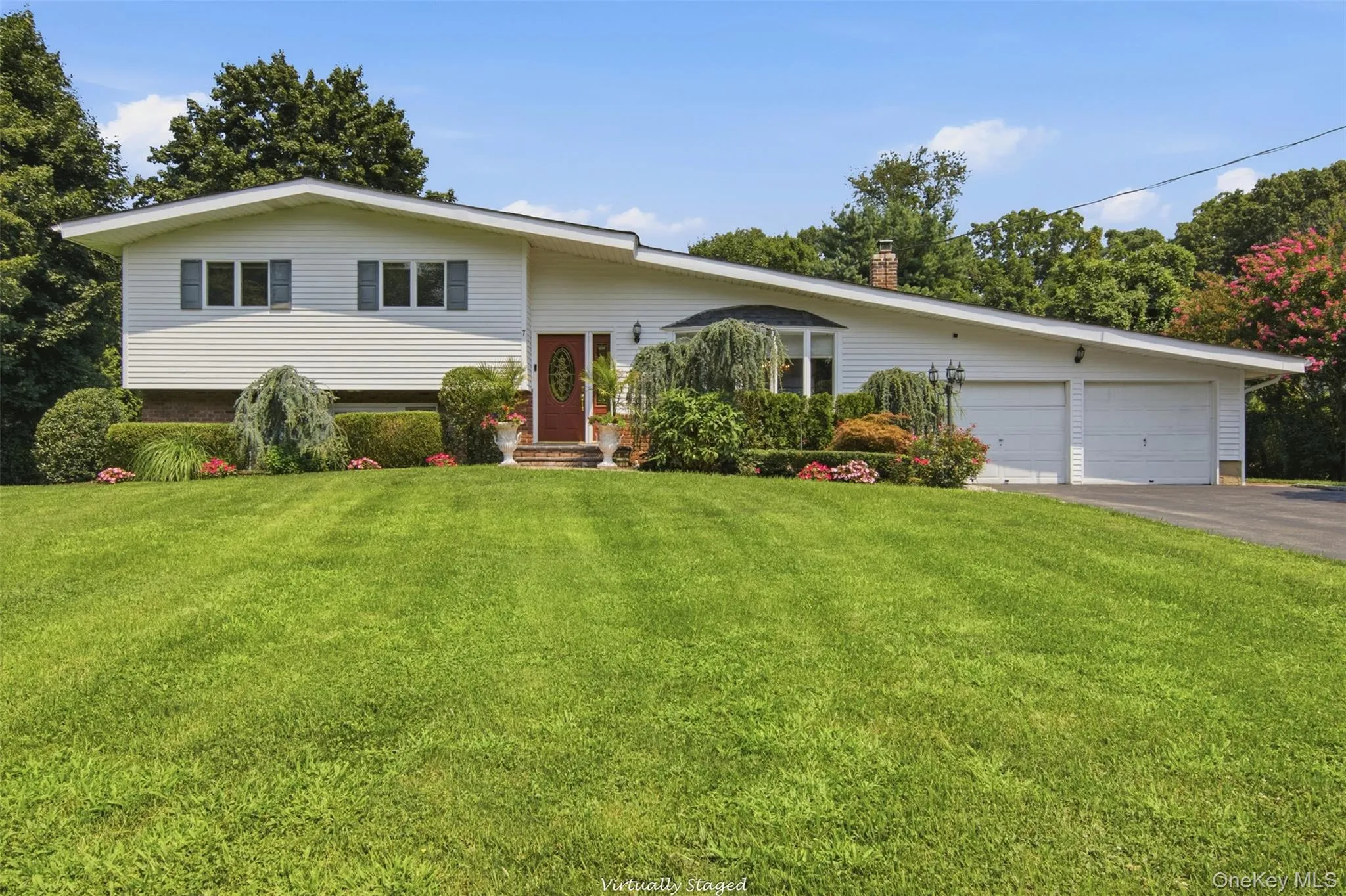 White siding exterior with a red entry door, bay window, and attached two-car garage White siding exterior with a red entry door, bay window, and attached two-car garage