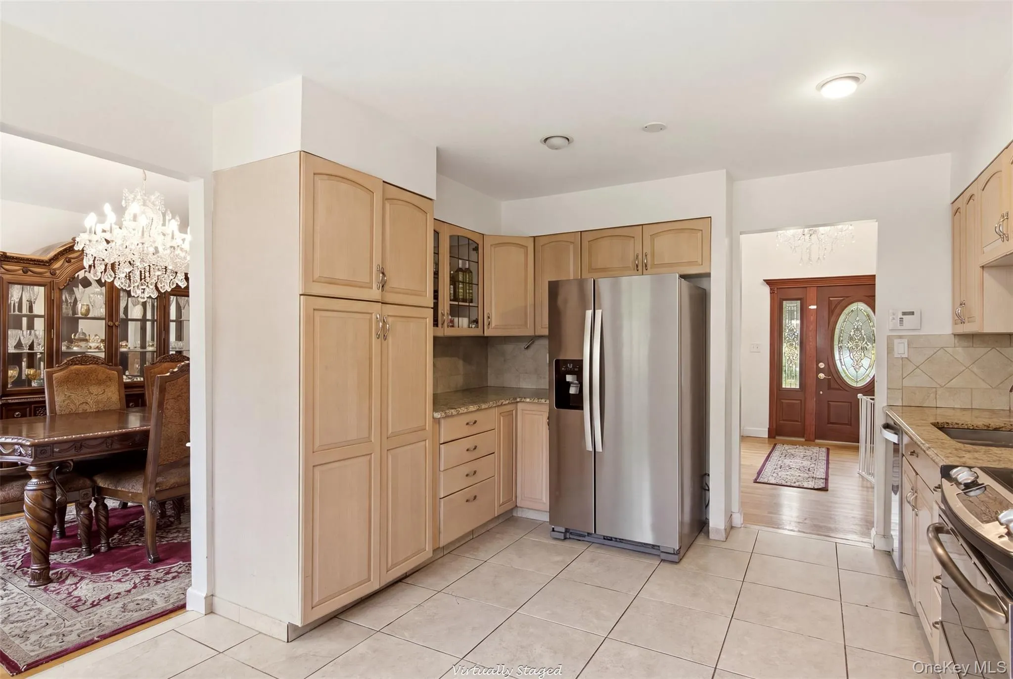 Kitchen featuring wood-finish cabinetry, tile flooring, stainless steel refrigerator, and granite countertops with tile backsplash Kitchen featuring wood-finish cabinetry, tile flooring, stainless steel refrigerator, and granite countertops with tile backsplash