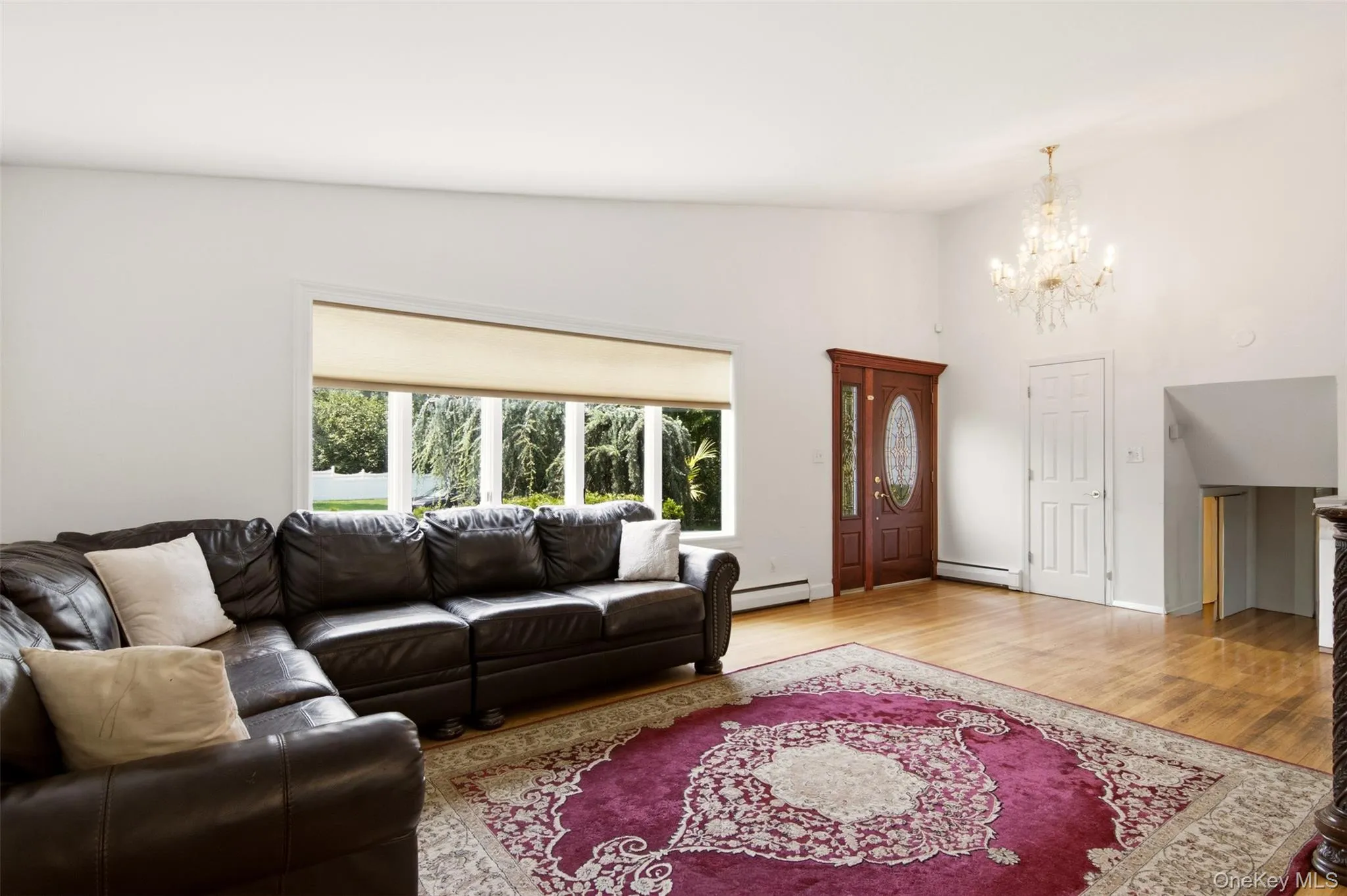 Hardwood flooring, crystal chandelier, decorative front door with oval glass insert, large windows, and white interior walls Hardwood flooring, crystal chandelier, decorative front door with oval glass insert, large windows, and white interior walls