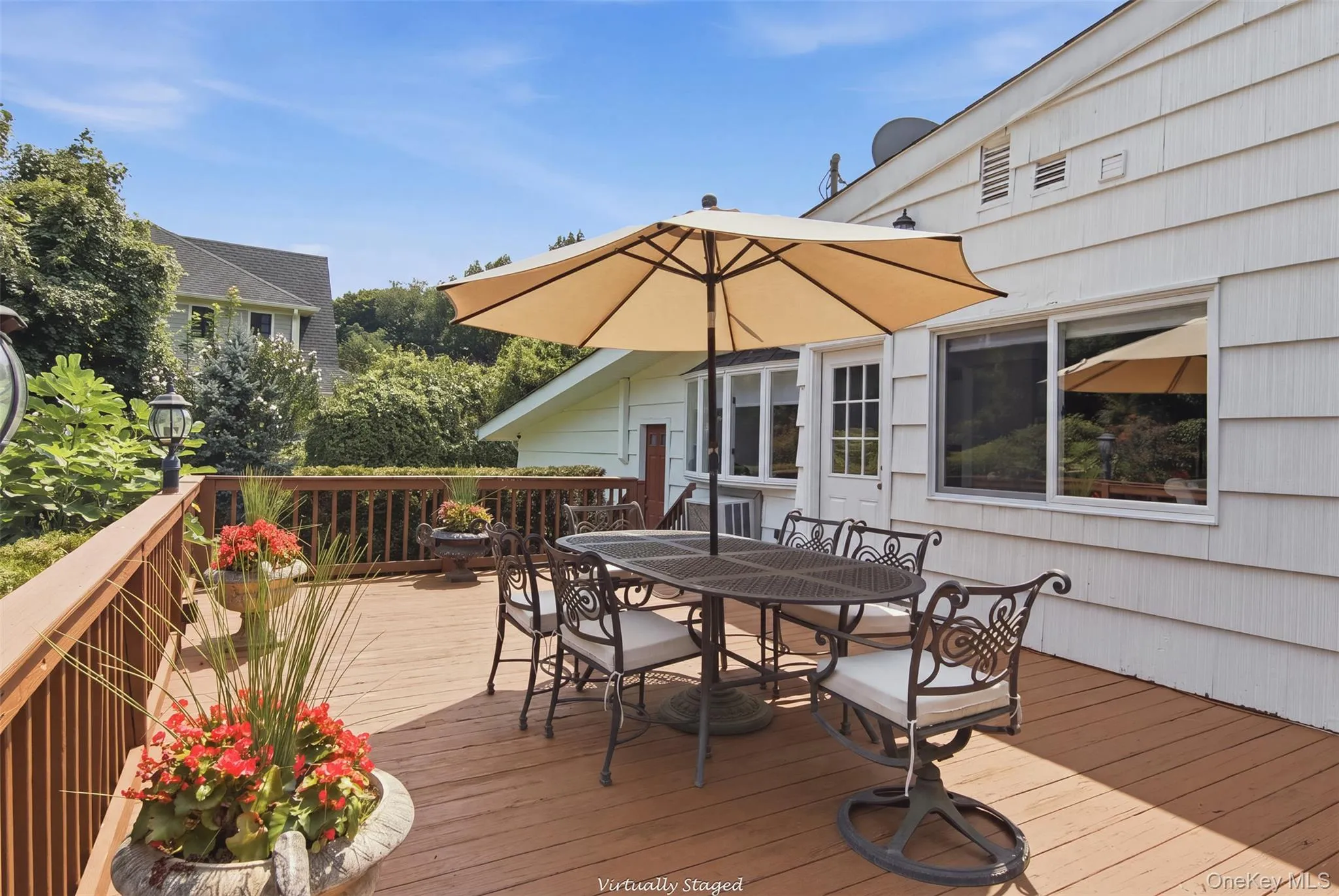 Expansive wood-finish deck with a wood railing and a white shingle exterior Expansive wood-finish deck with a wood railing and a white shingle exterior