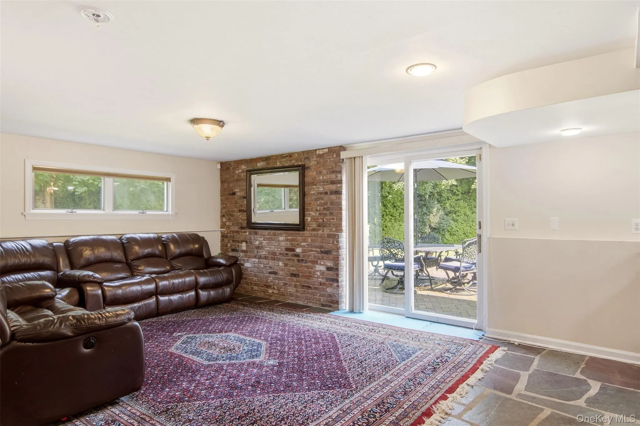 Exposed brick accent wall, recessed lighting, sliding glass door, multiple windows, and flagstone flooring Exposed brick accent wall, recessed lighting, sliding glass door, multiple windows, and flagstone flooring