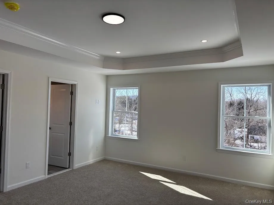 Carpeted spare room featuring crown molding and a tray ceiling Carpeted spare room featuring crown molding and a tray ceiling