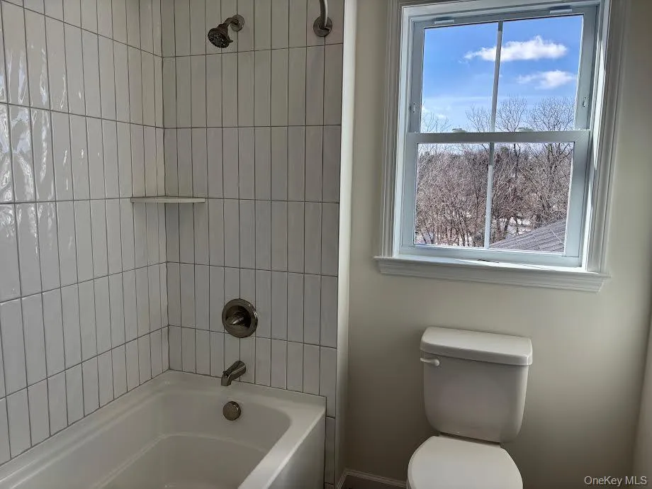 Bathroom with toilet and tiled shower / bath combo Bathroom with toilet and tiled shower / bath combo