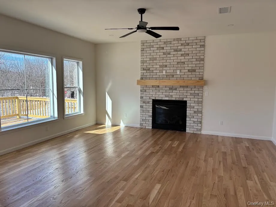 Unfurnished living room featuring a fireplace, ceiling fan, and wood-type flooring Unfurnished living room featuring a fireplace, ceiling fan, and wood-type flooring