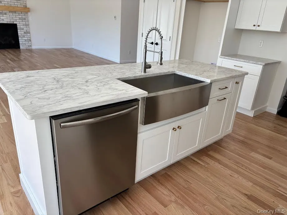 Kitchen with white cabinets, a kitchen island with sink, sink, and stainless steel dishwasher Kitchen with white cabinets, a kitchen island with sink, sink, and stainless steel dishwasher