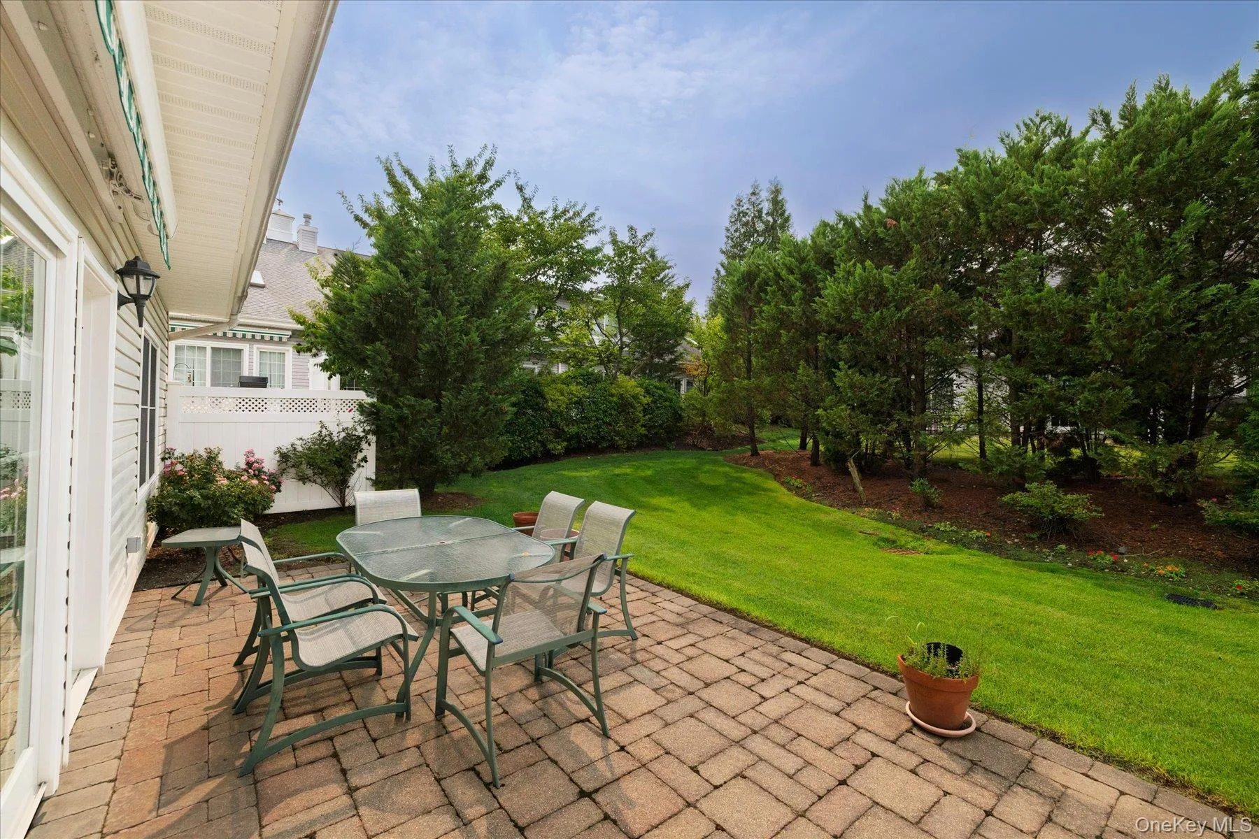 Paver patio featuring a sloped lawn and mature perimeter trees Paver patio featuring a sloped lawn and mature perimeter trees