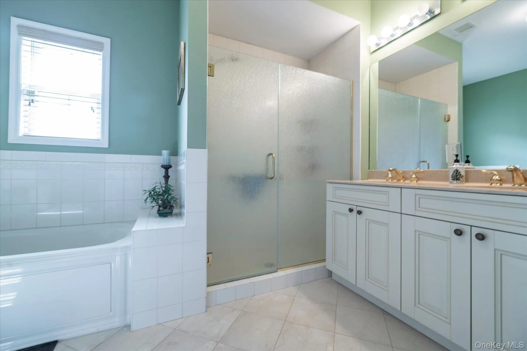 Dual vanity with undermount sinks, a built-in bathtub, a walk-in shower with frosted glass, and tile flooring Dual vanity with undermount sinks, a built-in bathtub, a walk-in shower with frosted glass, and tile flooring