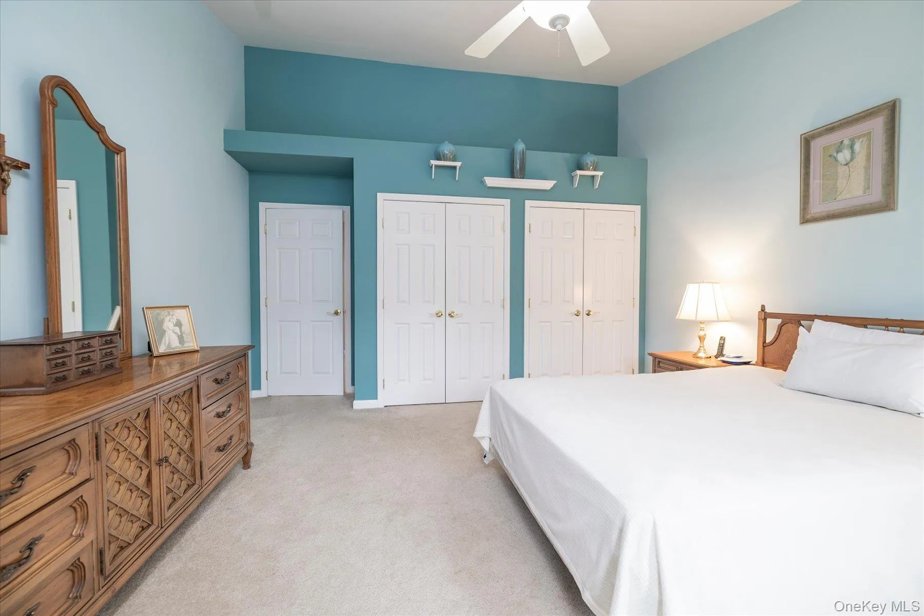 Vaulted ceiling with a ceiling fan, carpet flooring, two paneled closet doors, and an additional paneled door Vaulted ceiling with a ceiling fan, carpet flooring, two paneled closet doors, and an additional paneled door