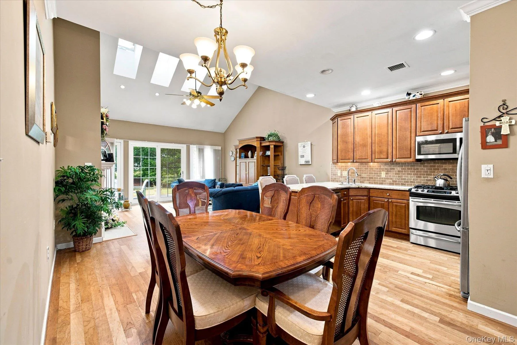Open-concept living space with wood-finish flooring, vaulted ceilings with skylights, and recessed lighting Open-concept living space with wood-finish flooring, vaulted ceilings with skylights, and recessed lighting