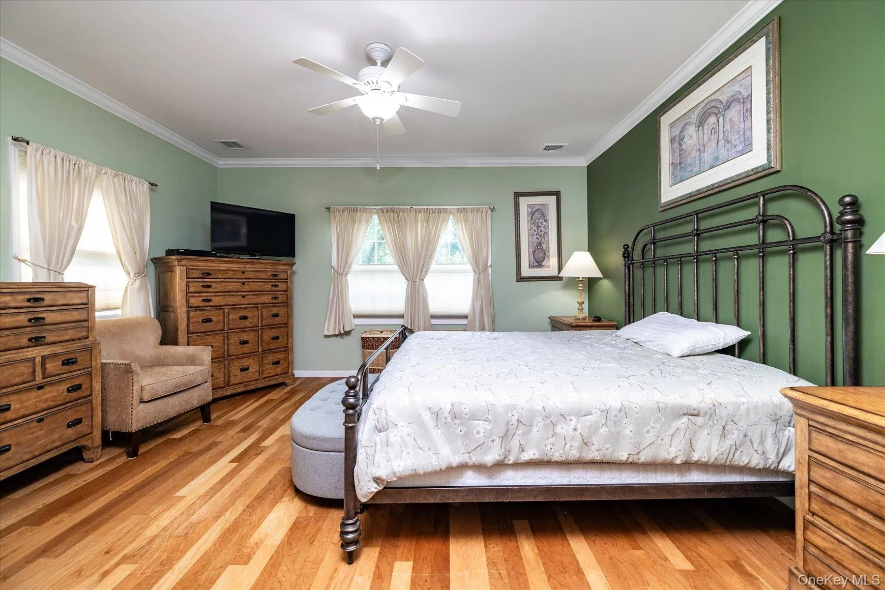Hardwood flooring, painted walls, crown molding, ceiling fan, and multiple windows Hardwood flooring, painted walls, crown molding, ceiling fan, and multiple windows