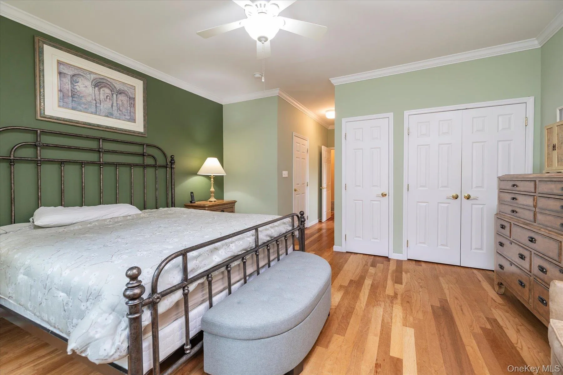 Hardwood flooring, painted walls, crown molding, double closet doors, and a ceiling fan with integrated lighting Hardwood flooring, painted walls, crown molding, double closet doors, and a ceiling fan with integrated lighting