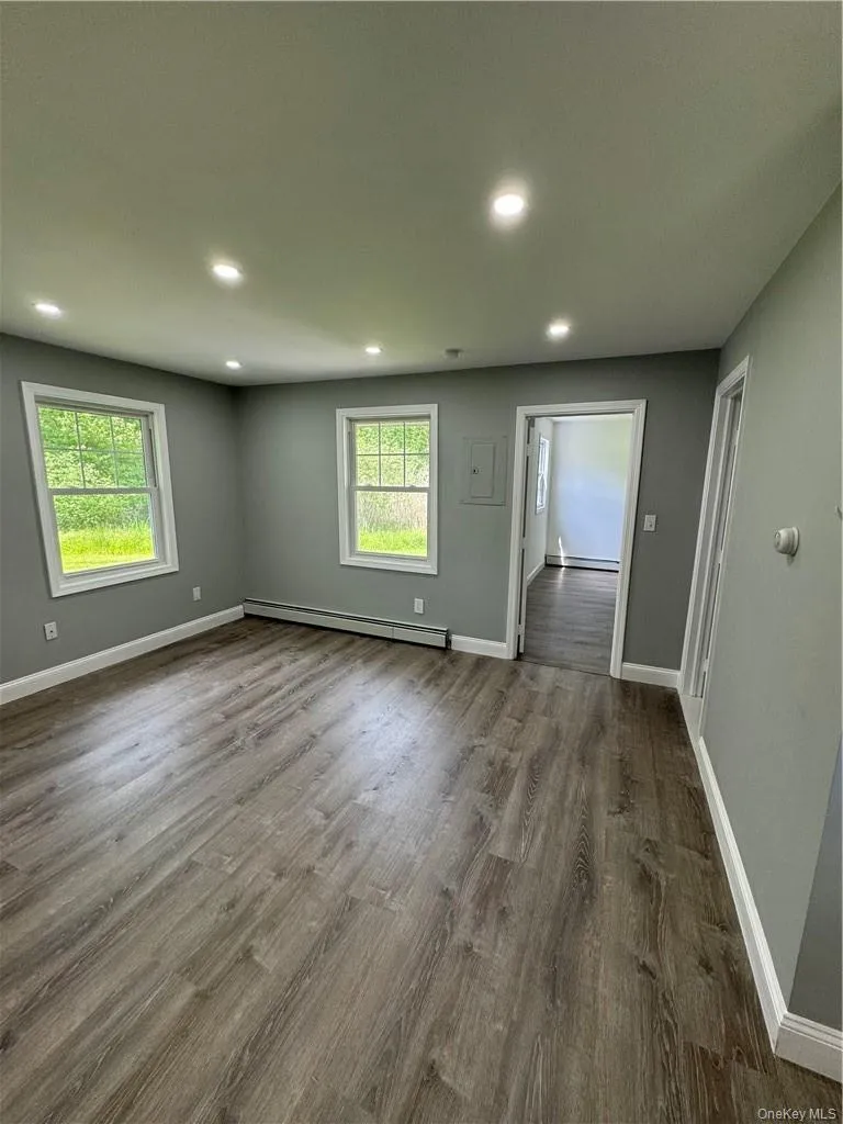 Spare room with plenty of natural light, hardwood / wood-style flooring, and a baseboard heating unit Spare room with plenty of natural light, hardwood / wood-style flooring, and a baseboard heating unit
