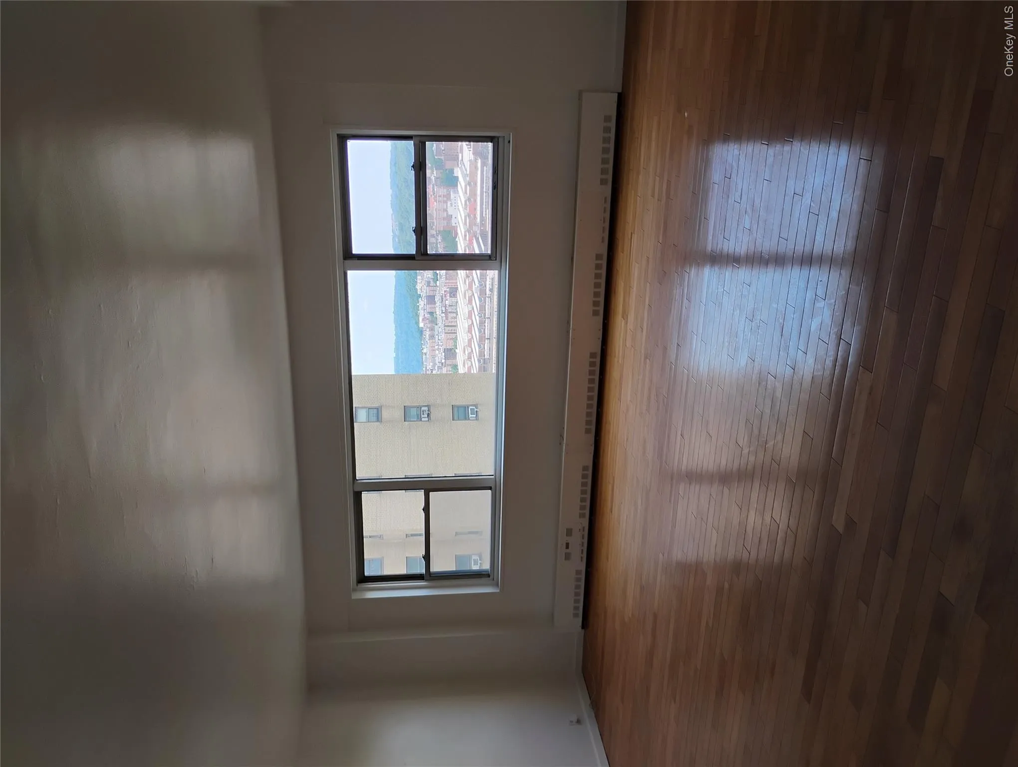 Hardwood flooring with a glossy finish, expansive multi-pane window, and baseboard heating unit Hardwood flooring with a glossy finish, expansive multi-pane window, and baseboard heating unit