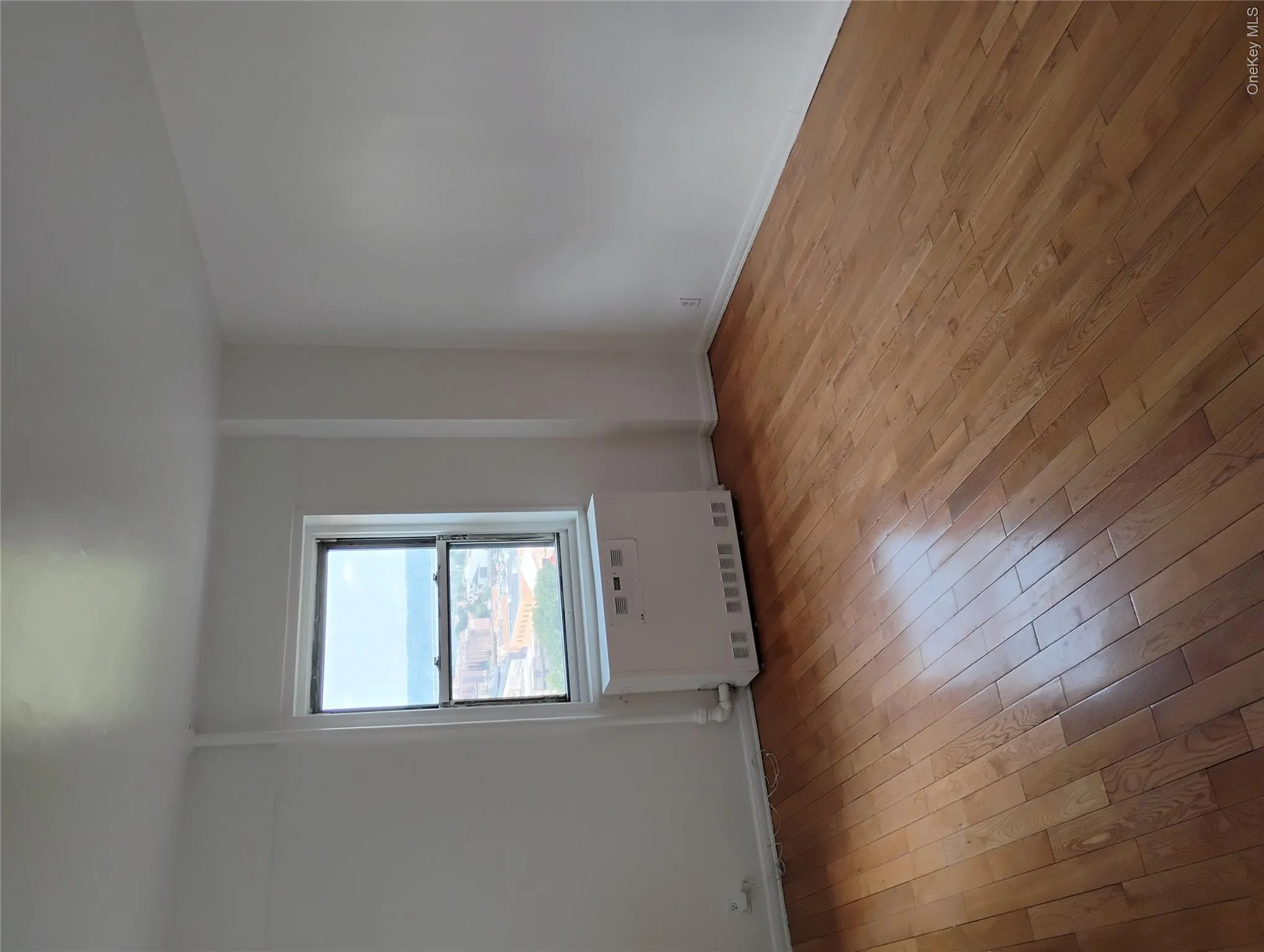 Hardwood flooring, painted white walls, and a casement window Hardwood flooring, painted white walls, and a casement window