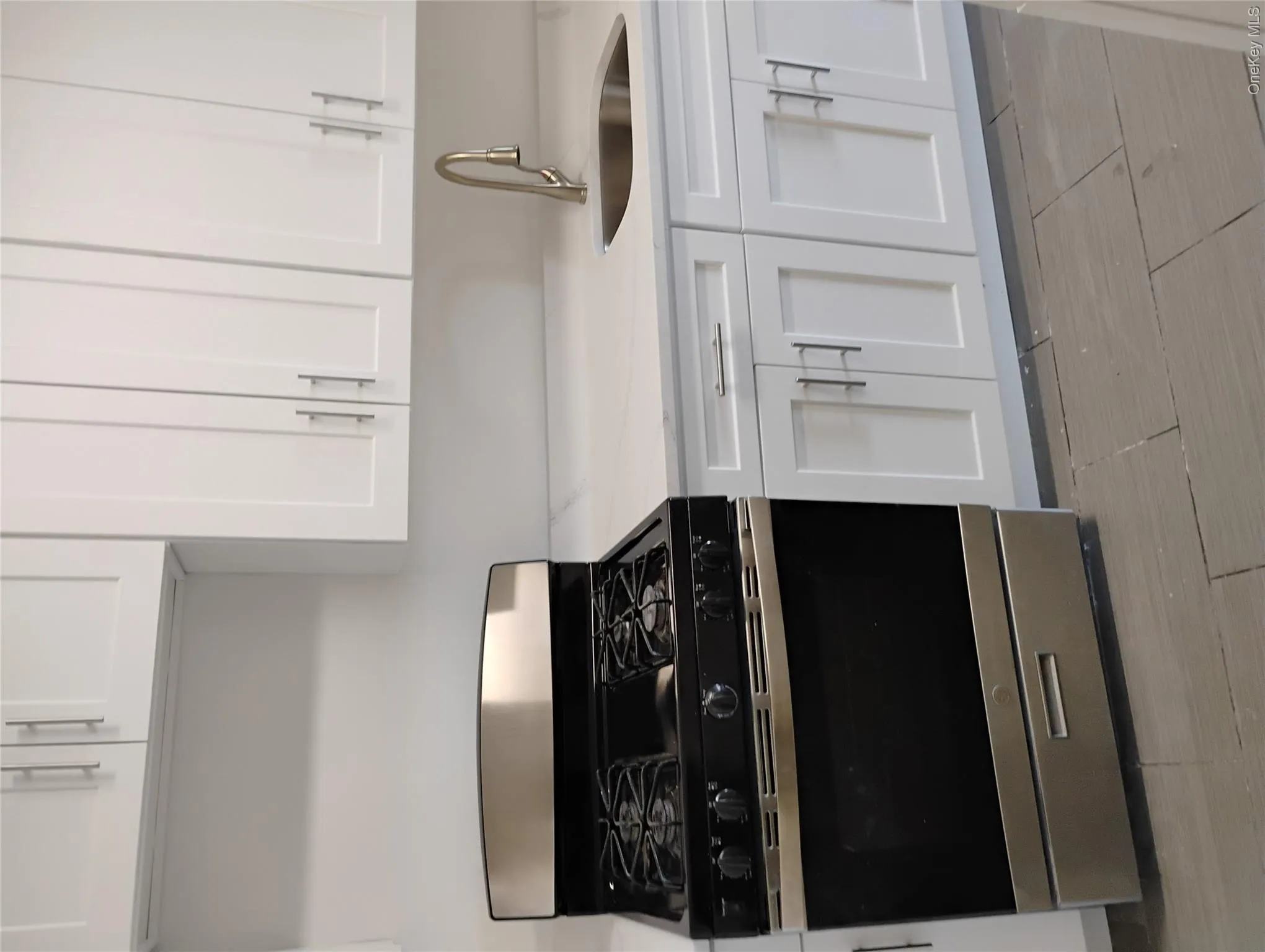 White shaker-style cabinetry, stainless steel gas range, stainless steel undermount sink, gooseneck faucet, and light-colored countertops White shaker-style cabinetry, stainless steel gas range, stainless steel undermount sink, gooseneck faucet, and light-colored countertops