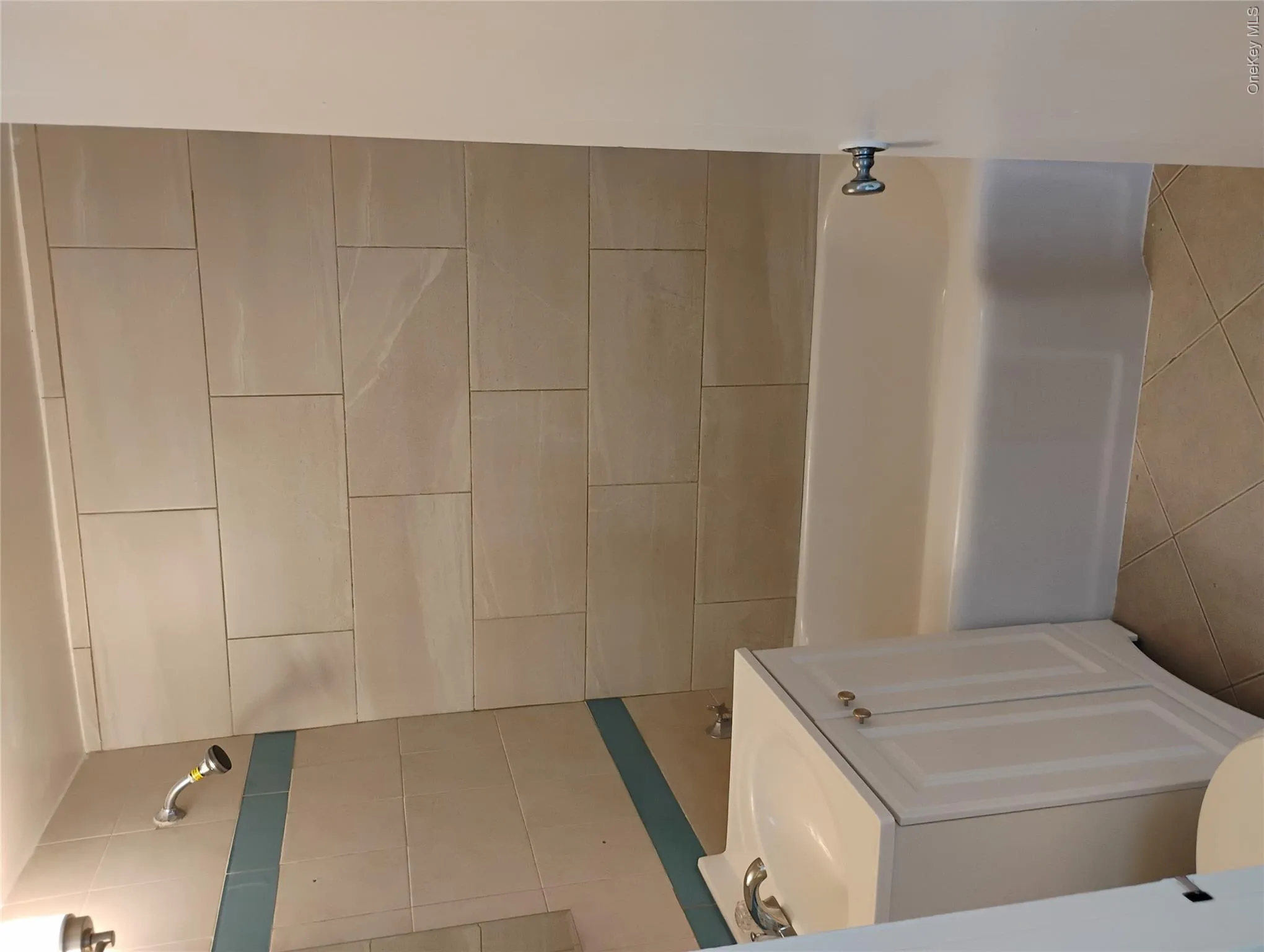 Full-size bathtub with a chrome faucet, large format rectangular wall tiles, and a white vanity with an integrated sink Full-size bathtub with a chrome faucet, large format rectangular wall tiles, and a white vanity with an integrated sink