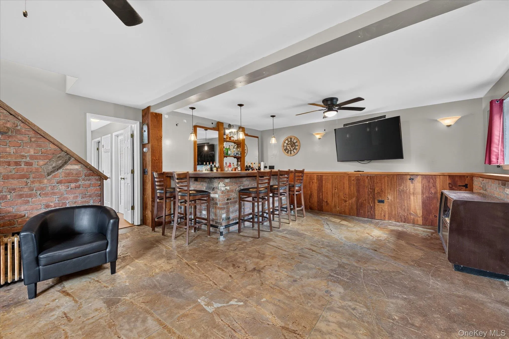 Exposed brick wall, built-in wet bar, wood paneling, ceiling fan, and sconce lighting Exposed brick wall, built-in wet bar, wood paneling, ceiling fan, and sconce lighting