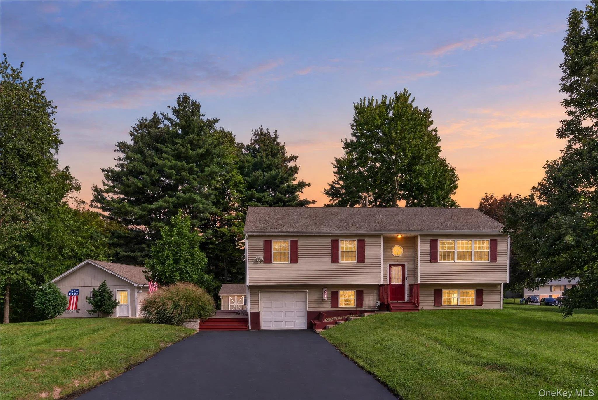 Split-level residence featuring a two-car garage, red entry door, and red window shutters Split-level residence featuring a two-car garage, red entry door, and red window shutters