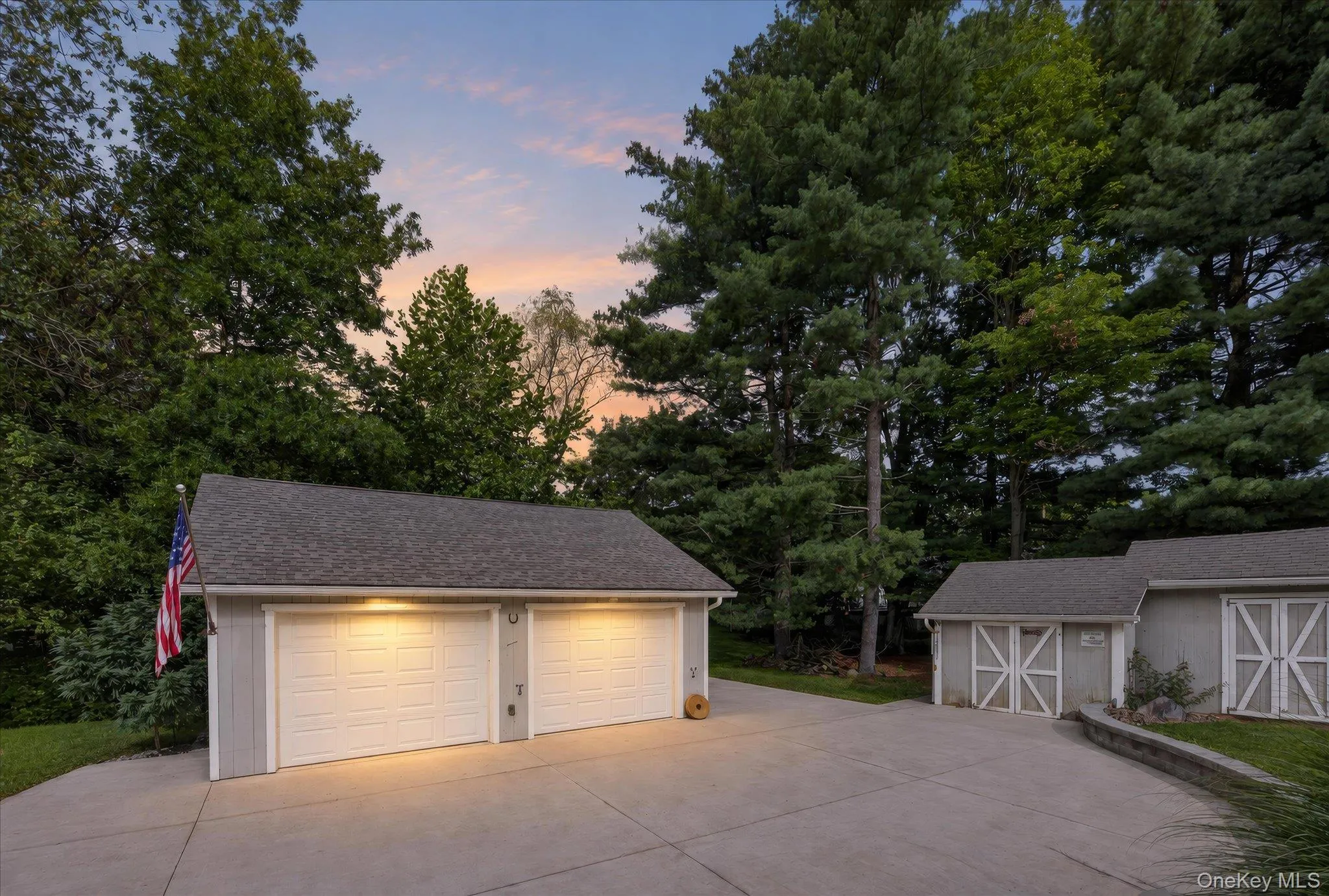 Detached two-car garage with overhead lighting, asphalt shingle roofing, and a concrete driveway Detached two-car garage with overhead lighting, asphalt shingle roofing, and a concrete driveway