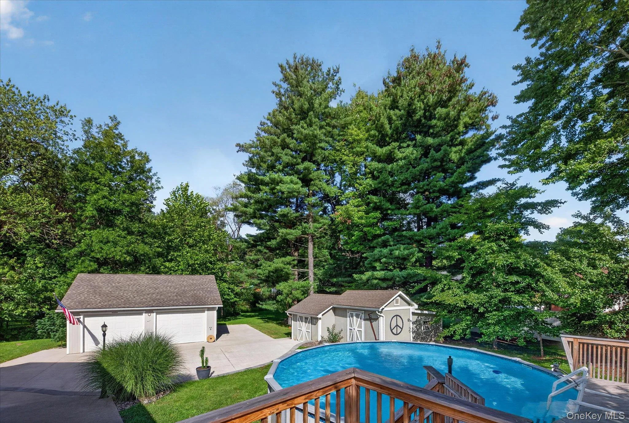 Expansive backyard with an above-ground pool, a detached two-car garage, and a separate shed Expansive backyard with an above-ground pool, a detached two-car garage, and a separate shed