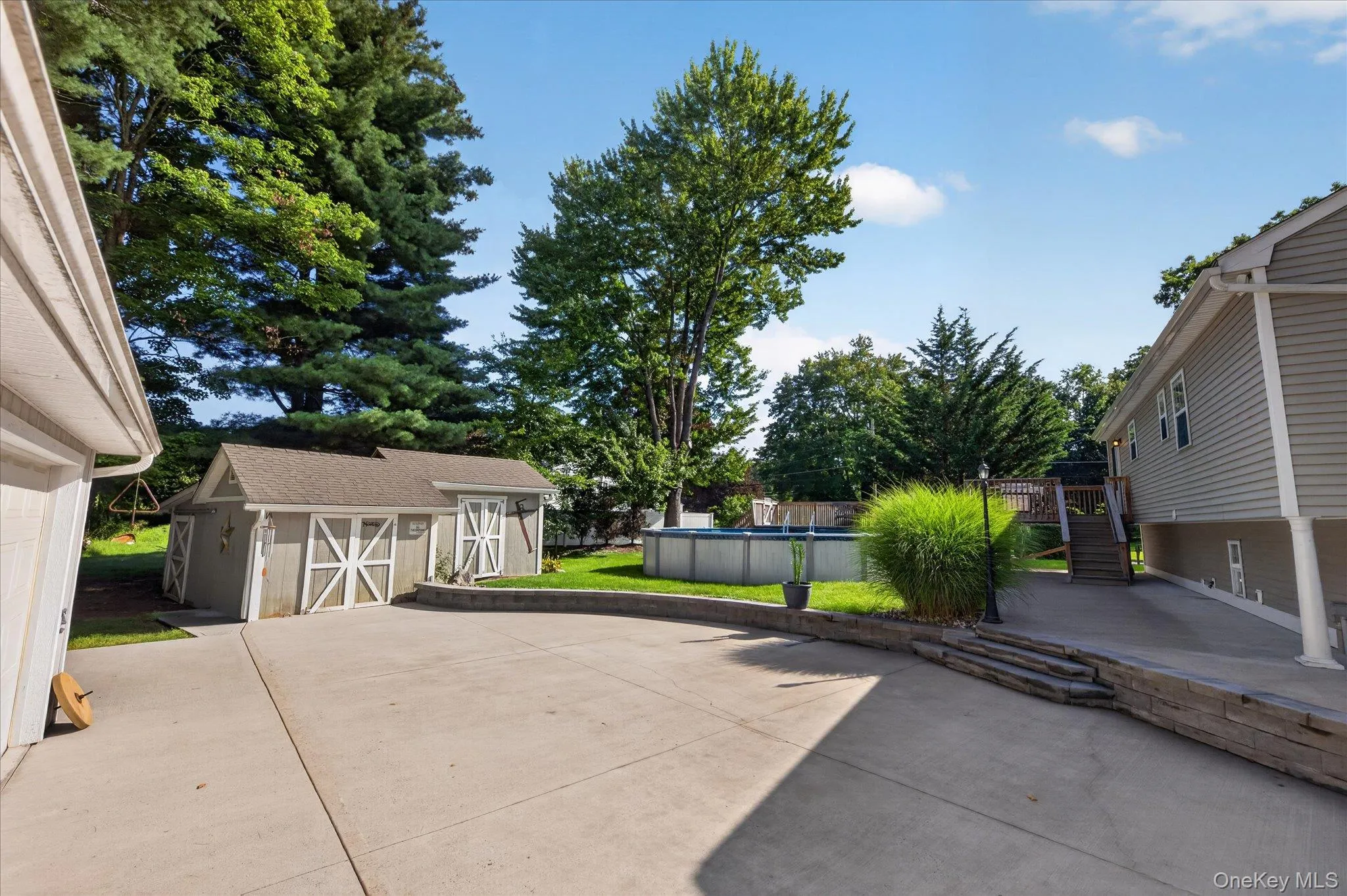 Expansive concrete driveway, two-door storage shed, retaining wall, above-ground pool, and wood deck Expansive concrete driveway, two-door storage shed, retaining wall, above-ground pool, and wood deck