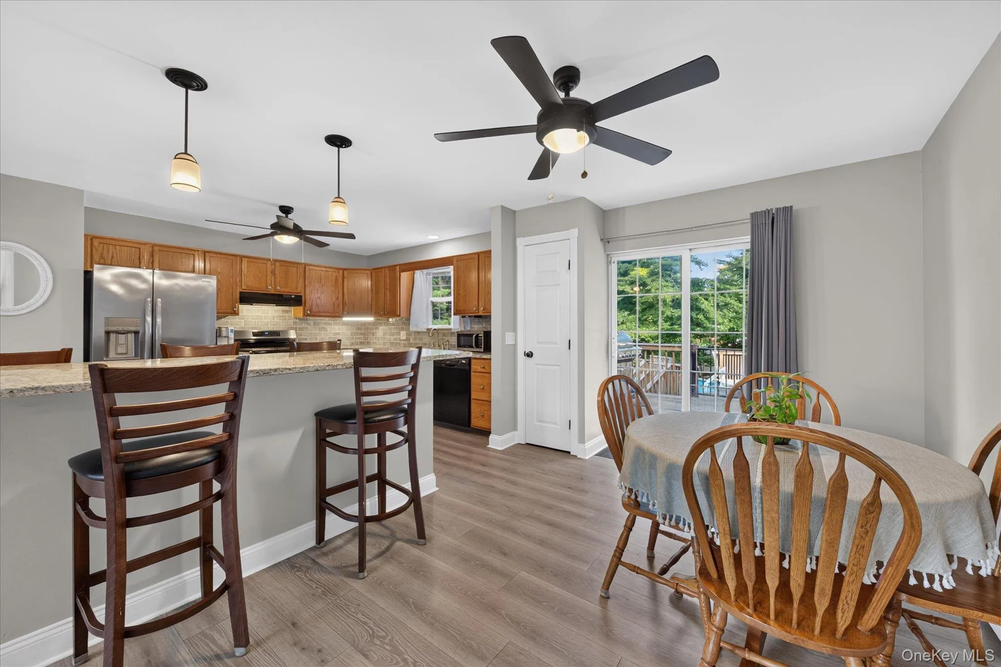 Kitchen with wood-finish flooring, recessed lighting, and a breakfast bar with stone countertops Kitchen with wood-finish flooring, recessed lighting, and a breakfast bar with stone countertops