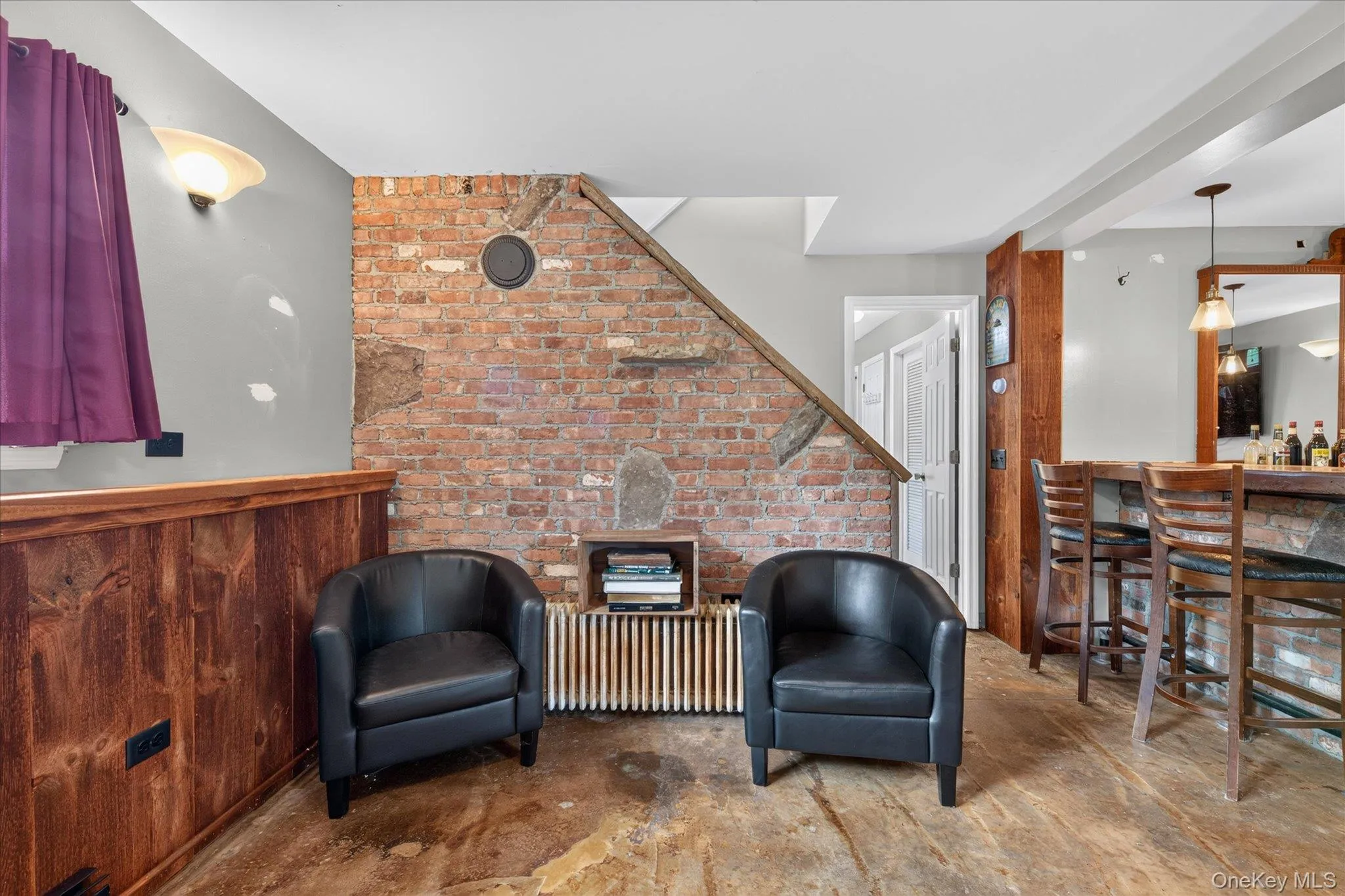 Exposed brick wall detail, wood-finish flooring, wood paneling, built-in bar, and sconce lighting Exposed brick wall detail, wood-finish flooring, wood paneling, built-in bar, and sconce lighting