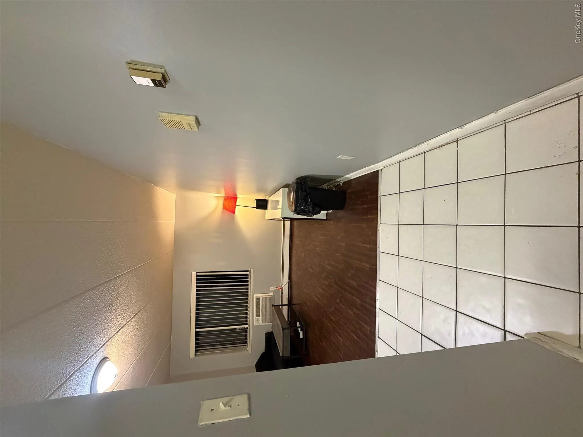Hall with tile patterned flooring, a textured ceiling, and an AC wall unit Hall with tile patterned flooring, a textured ceiling, and an AC wall unit