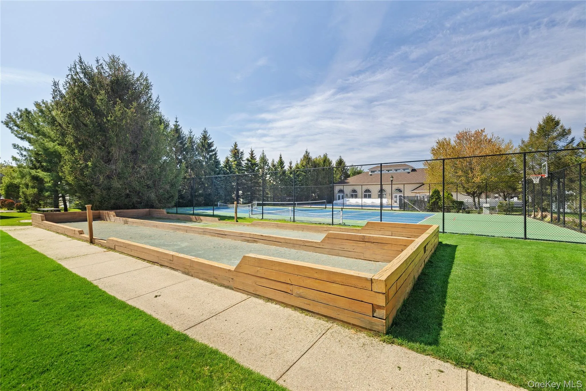 Bocce ball court with wood-finish perimeter, hardscaped pathway, and manicured lawn Bocce ball court with wood-finish perimeter, hardscaped pathway, and manicured lawn