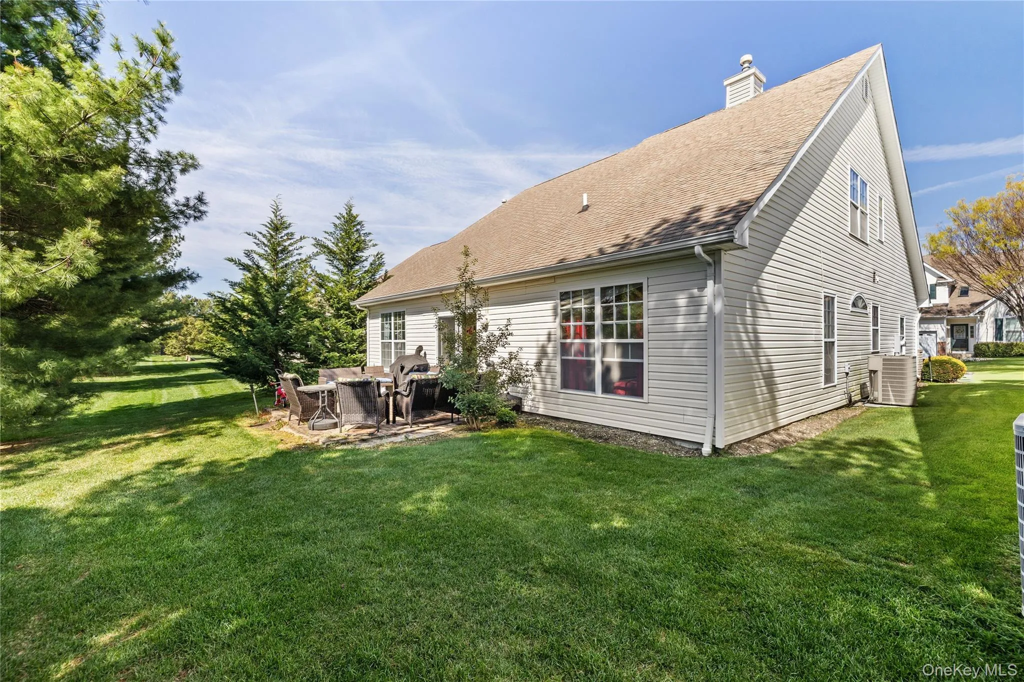 Expansive backyard featuring a stone patio, manicured lawn, and mature trees Expansive backyard featuring a stone patio, manicured lawn, and mature trees
