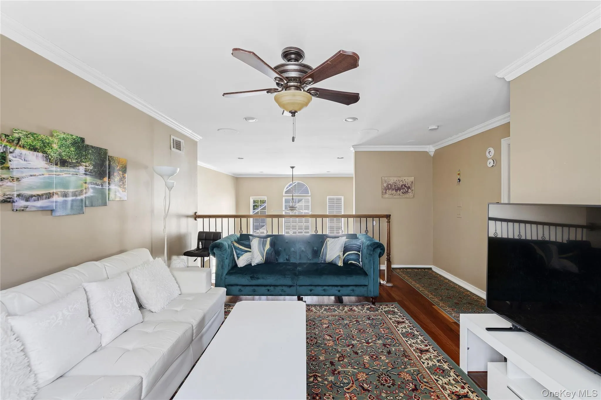 Recessed lighting, crown molding, ceiling fan, wood-finish flooring, and a second-story railing Recessed lighting, crown molding, ceiling fan, wood-finish flooring, and a second-story railing