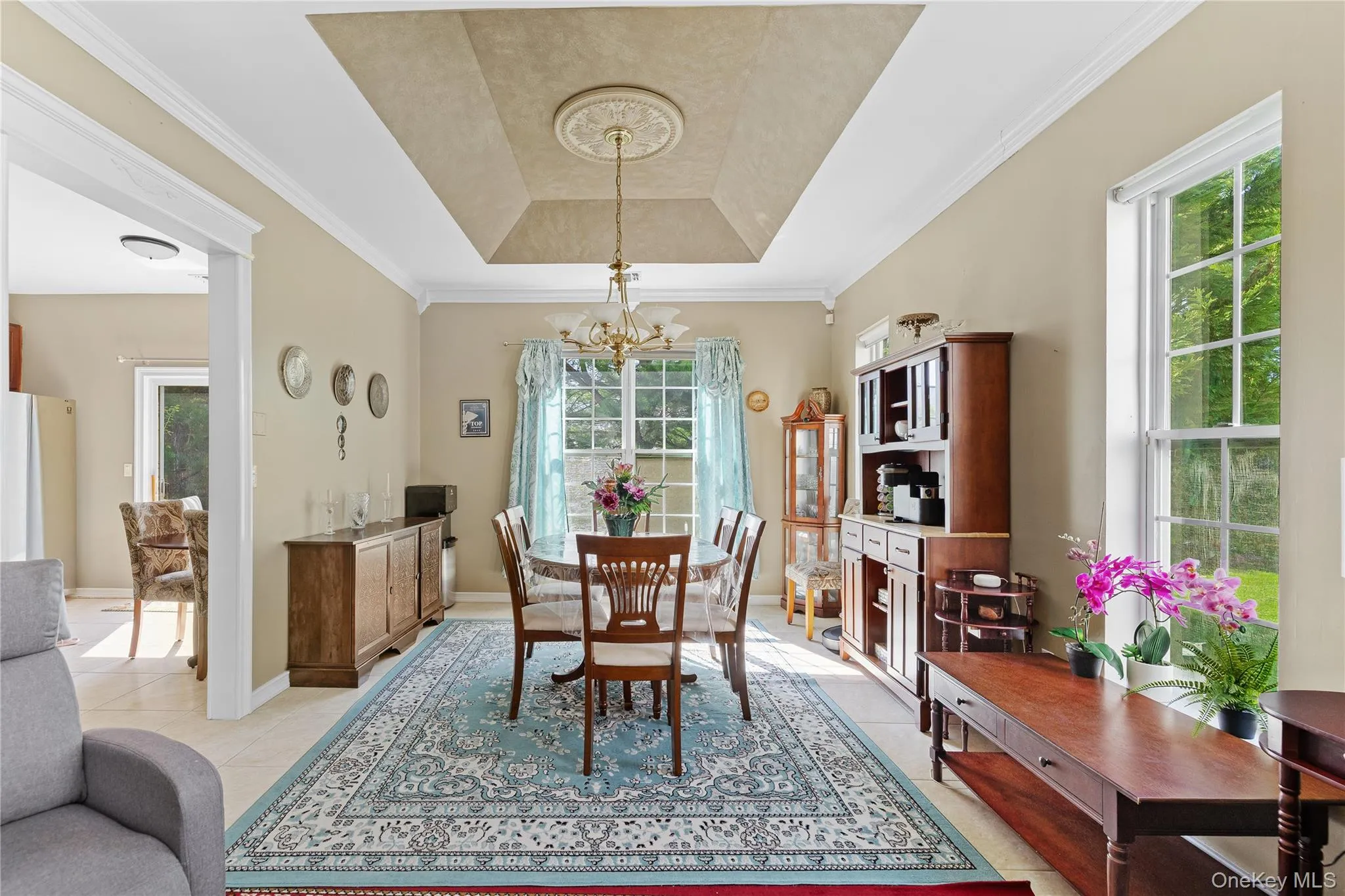 Tray ceiling with decorative medallion, chandelier lighting, and large windows Tray ceiling with decorative medallion, chandelier lighting, and large windows