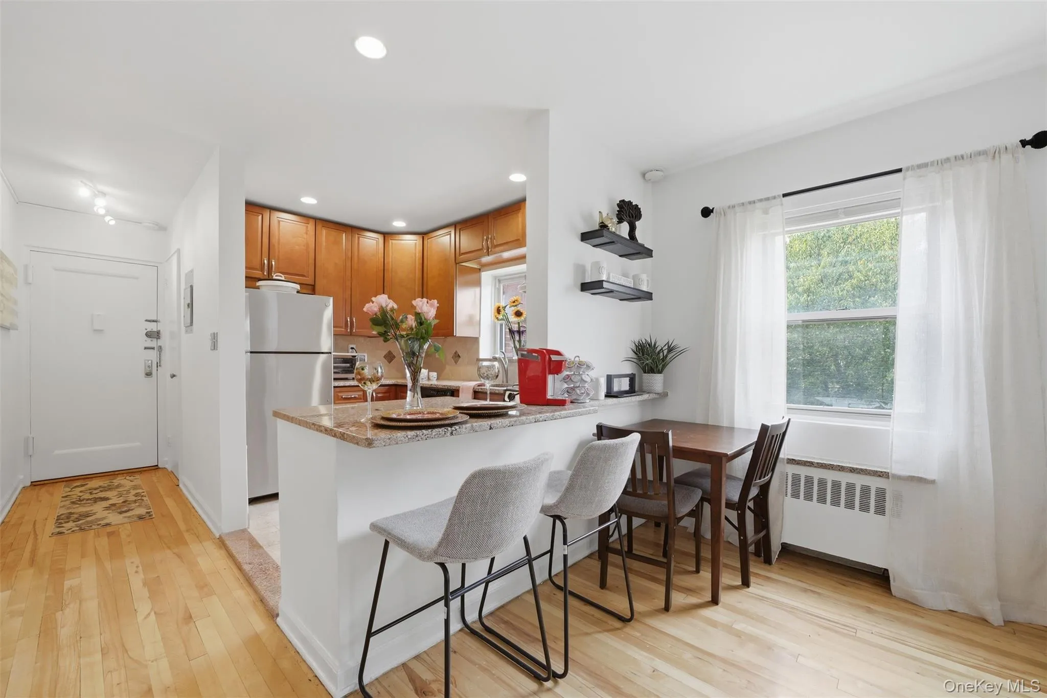 Bright and open eat-in kitchen featuring a breakfast bar, dedicated dining space, and hardwood floors throughout. Bright and open eat-in kitchen featuring a breakfast bar, dedicated dining space, and hardwood floors throughout.