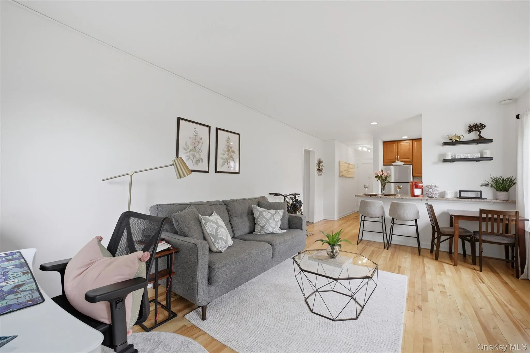 Open-concept living space featuring light hardwood floors, a dedicated workspace, and clear sightlines into the eat-in kitchen. Open-concept living space featuring light hardwood floors, a dedicated workspace, and clear sightlines into the eat-in kitchen.
