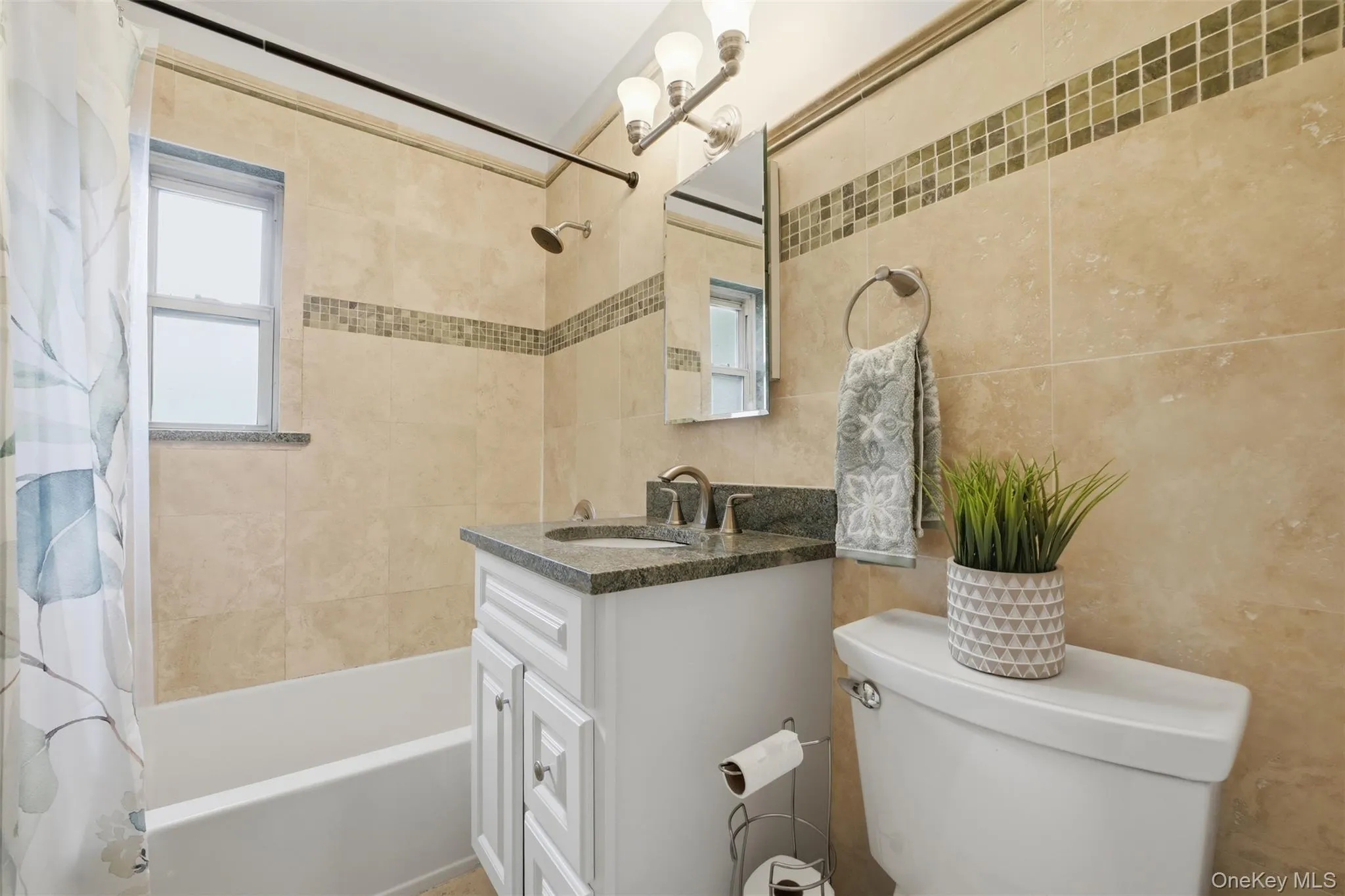 Get ready for the day in this immaculate bathroom! The space boasts a beautiful vanity with stone counters, a natural light-filled window in the shower, and clean, neutral tilework throughout. Get ready for the day in this immaculate bathroom! The space boasts a beautiful vanity with stone counters, a natural light-filled window in the shower, and clean, neutral tilework throughout.