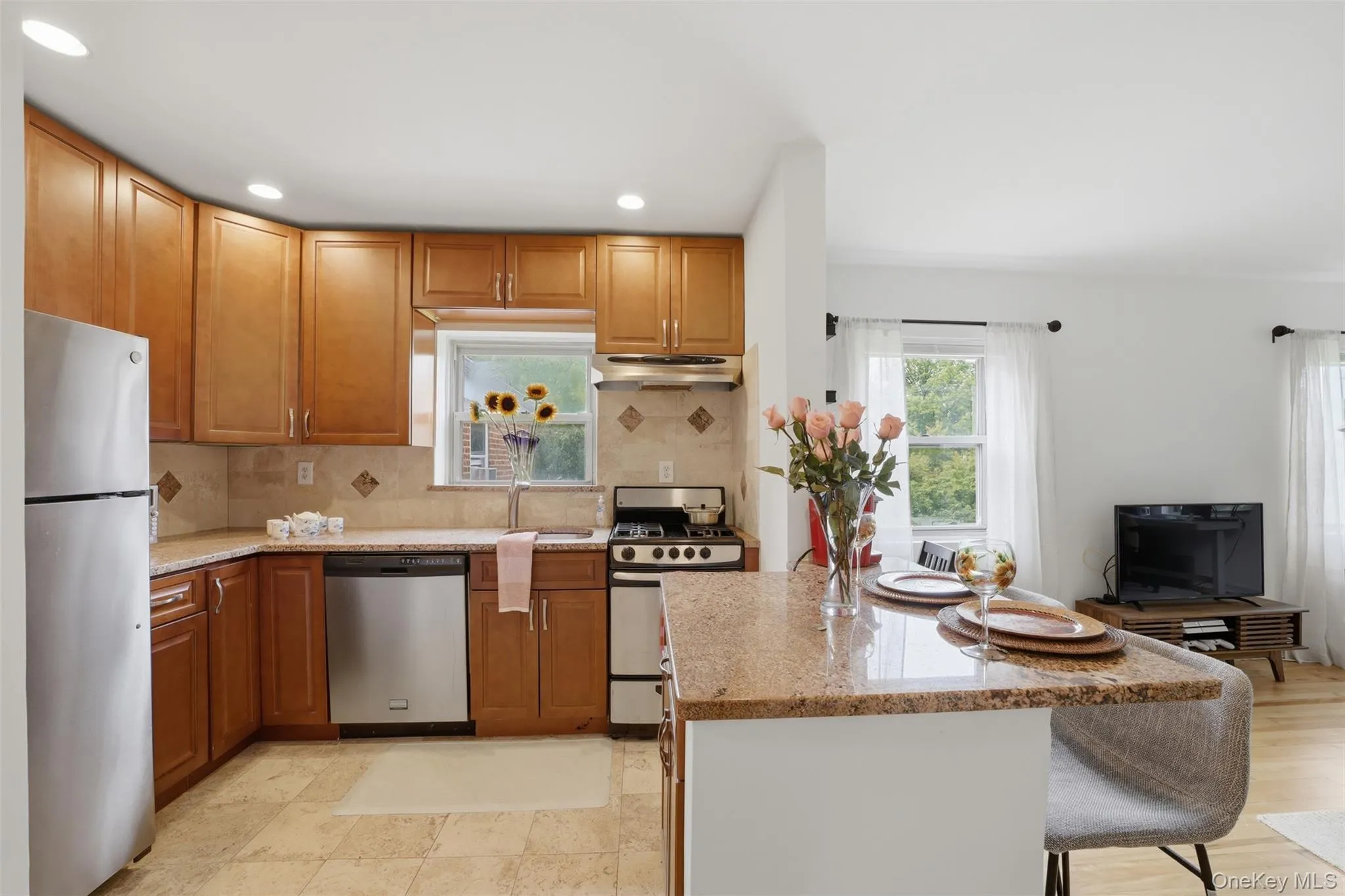 Inviting eat-in kitchen highlighting a large peninsula with bar seating, beautiful stone counters, and seamless integration with the bright living space. Inviting eat-in kitchen highlighting a large peninsula with bar seating, beautiful stone counters, and seamless integration with the bright living space.