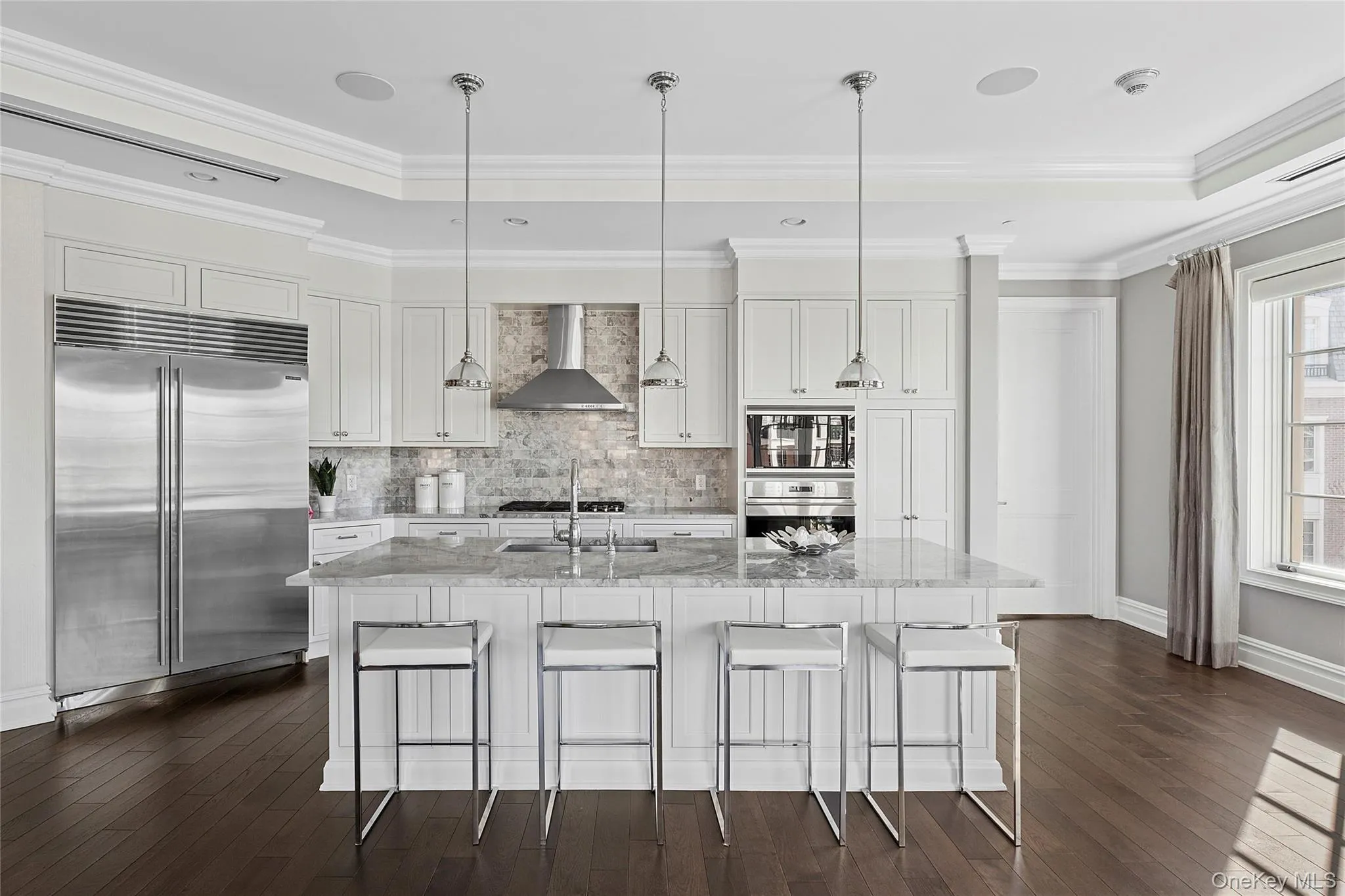 Kitchen featuring decorative backsplash, built in refrigerator, white cabinets, dark wood-style floors, and wall chimney exhaust hood Kitchen featuring decorative backsplash, built in refrigerator, white cabinets, dark wood-style floors, and wall chimney exhaust hood